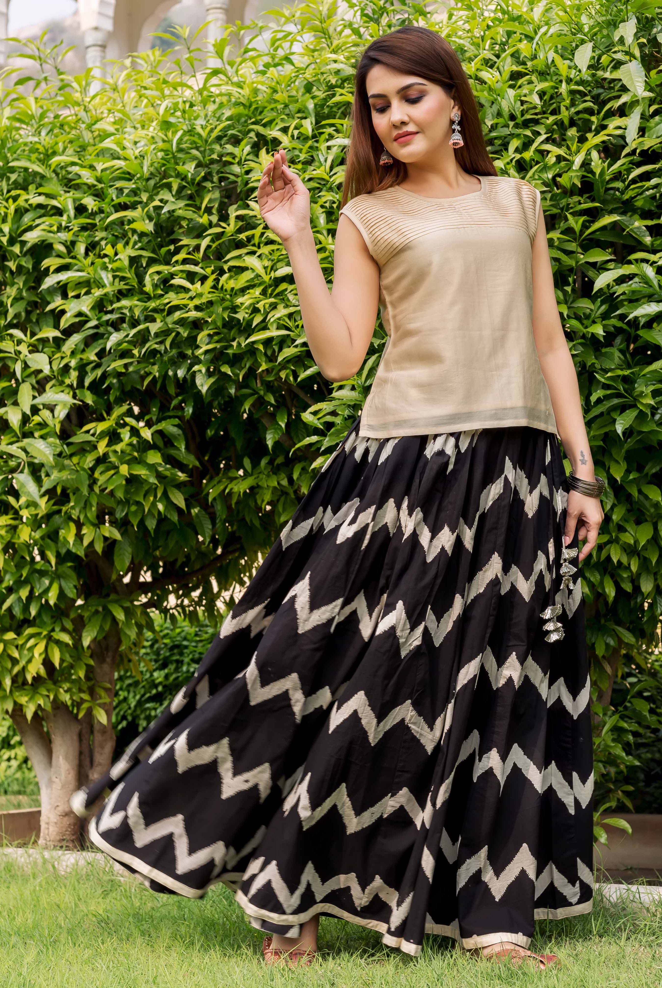 Front view model wearing beige sleeveless top with black and white chevron-printed long skirt.