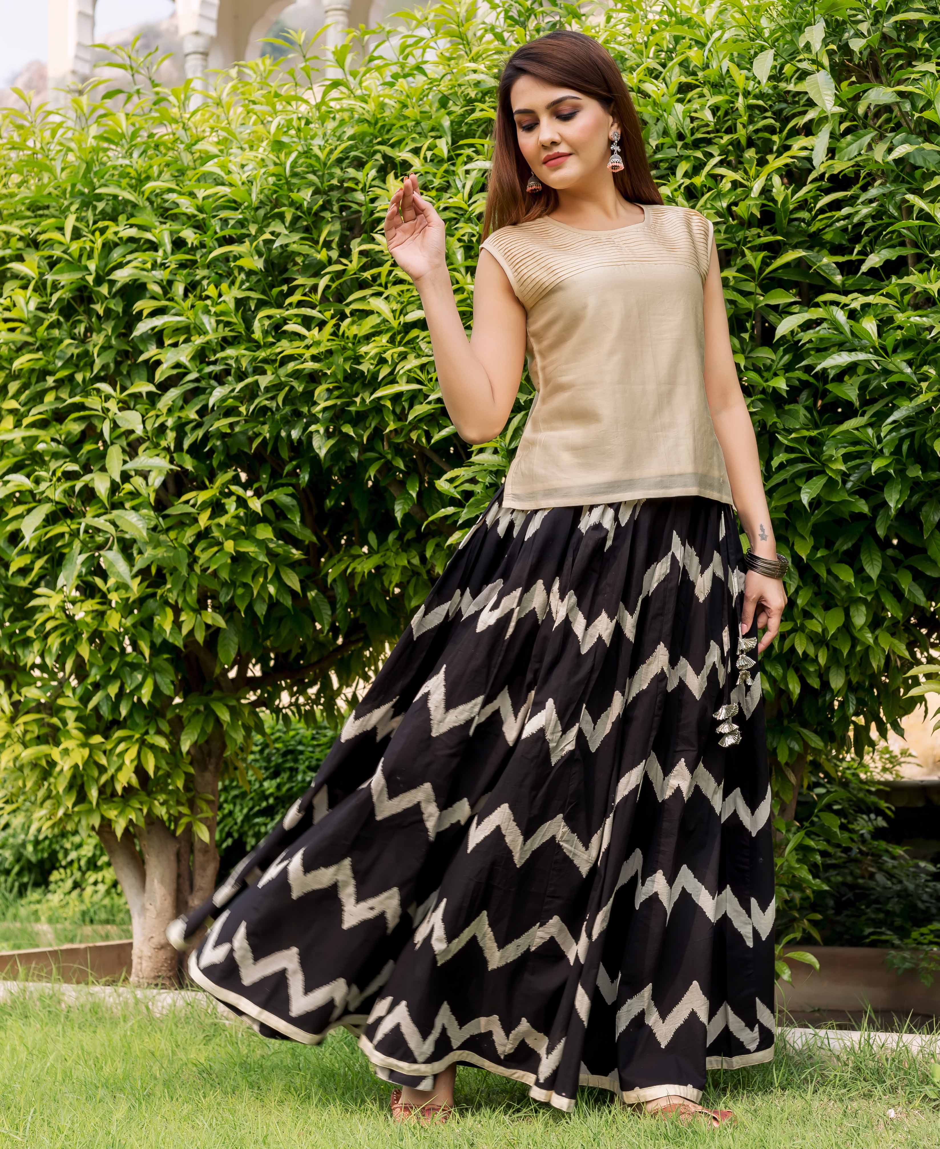 Front view model wearing beige sleeveless top with black and white chevron-printed long skirt.