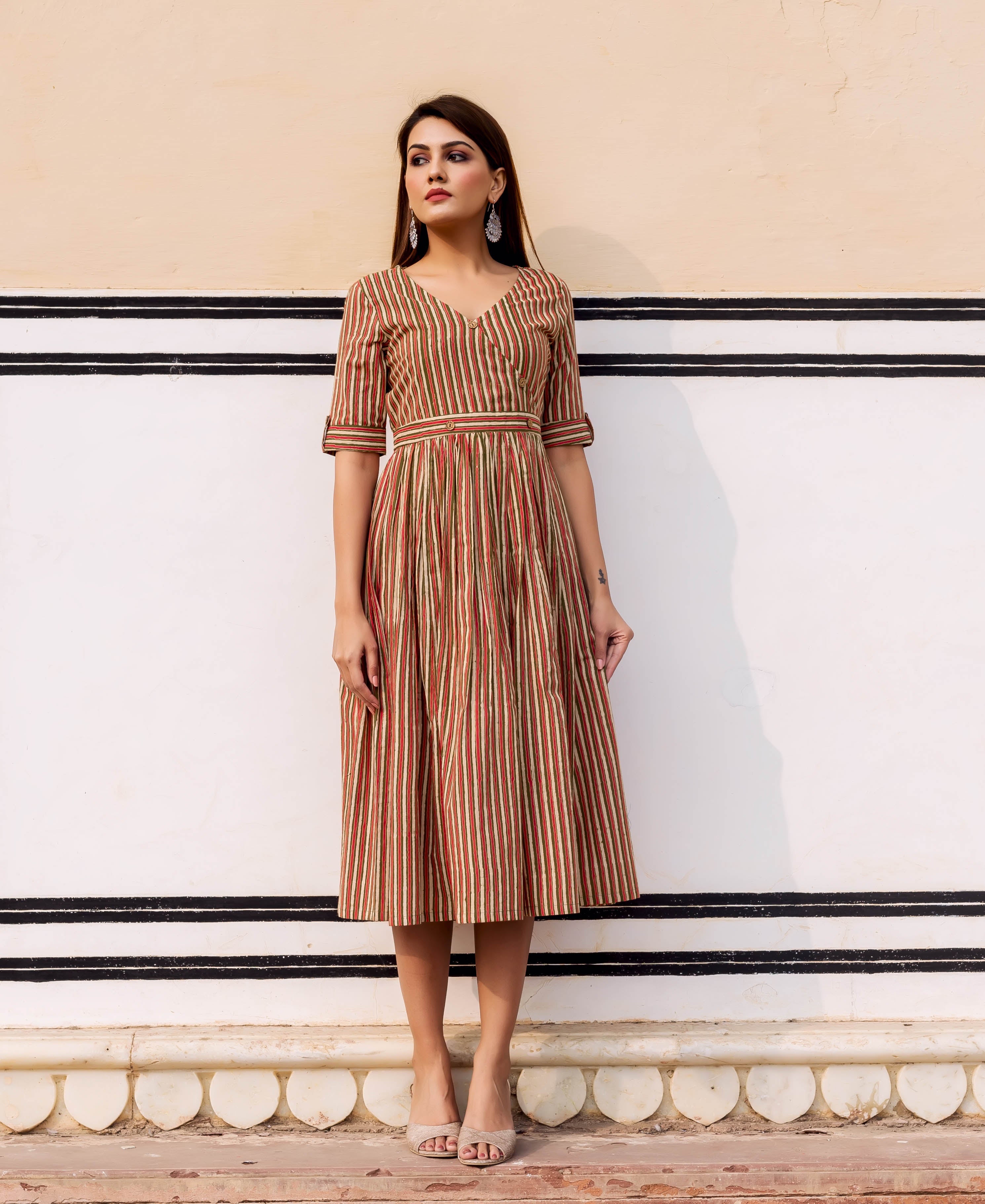 Standing model wearing a V-neck midi sundress with rustic red, olive, and cream vertical stripes.