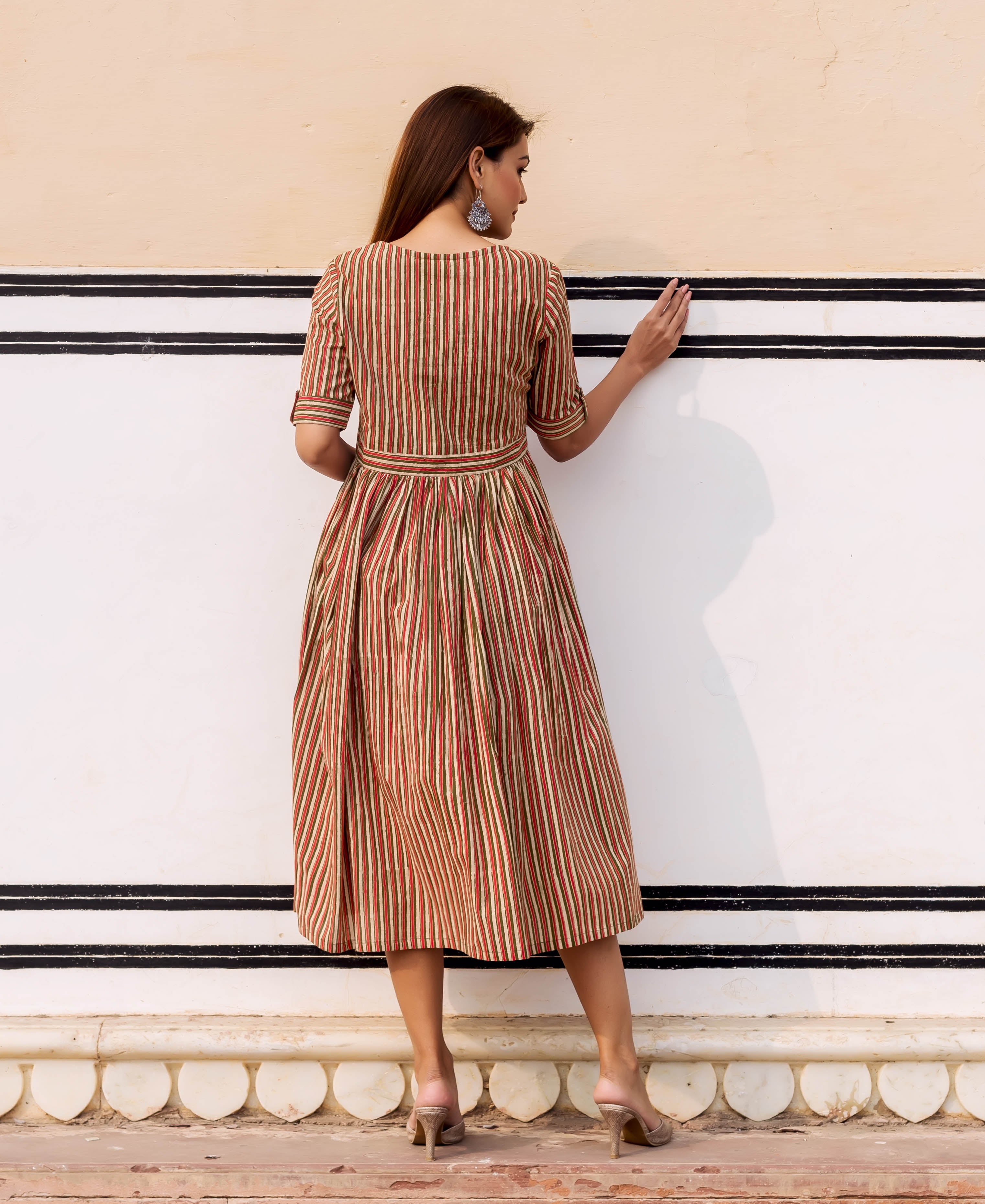 Model from back in a belted olive, rust, and cream striped hand-block printed sundress.