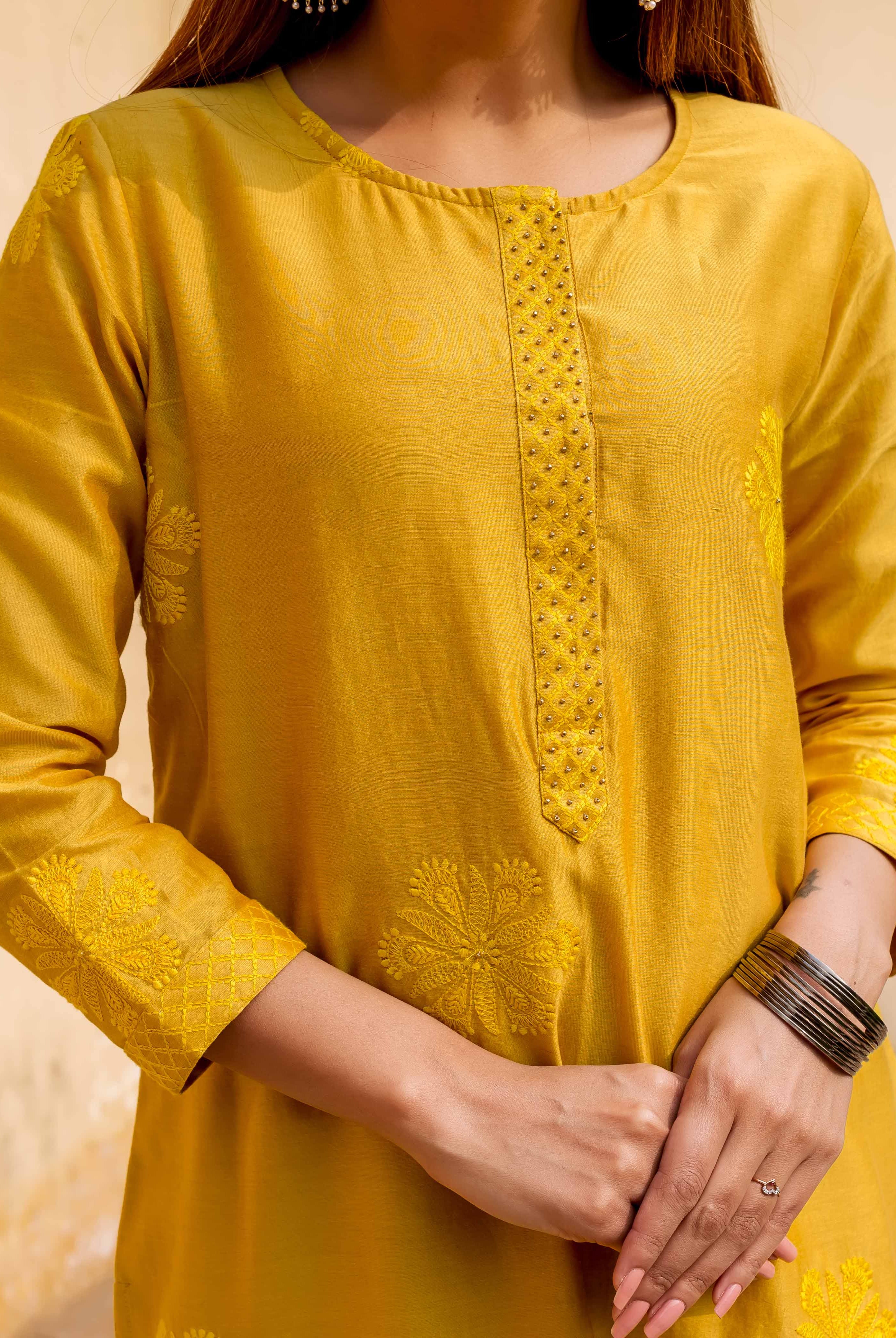 Model in carnation yellow hand embroidered kurta featuring intricate yoke and floral patterns.