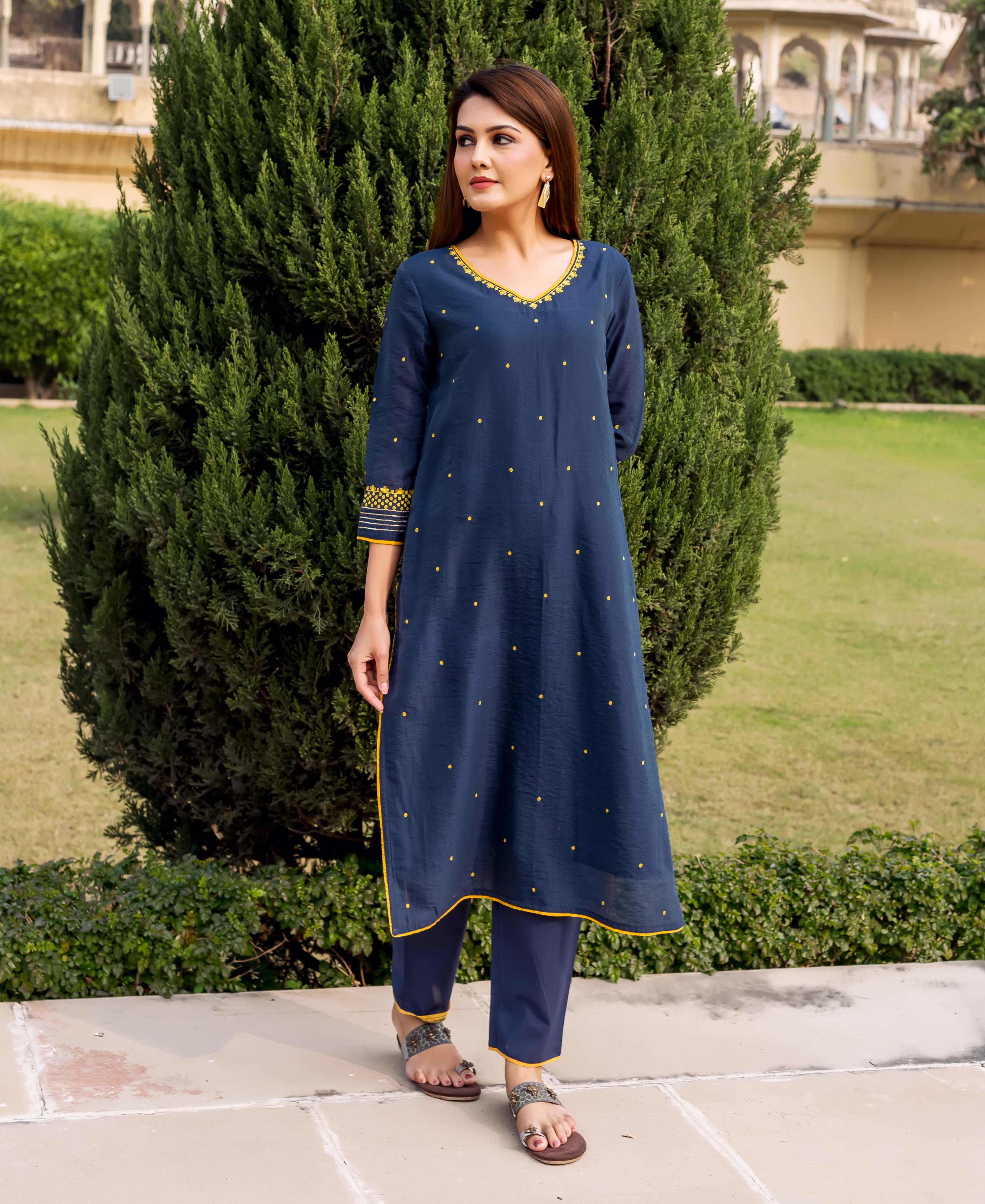 Navy blue embroidered kurta with yellow accents on a model outdoors in natural setting.