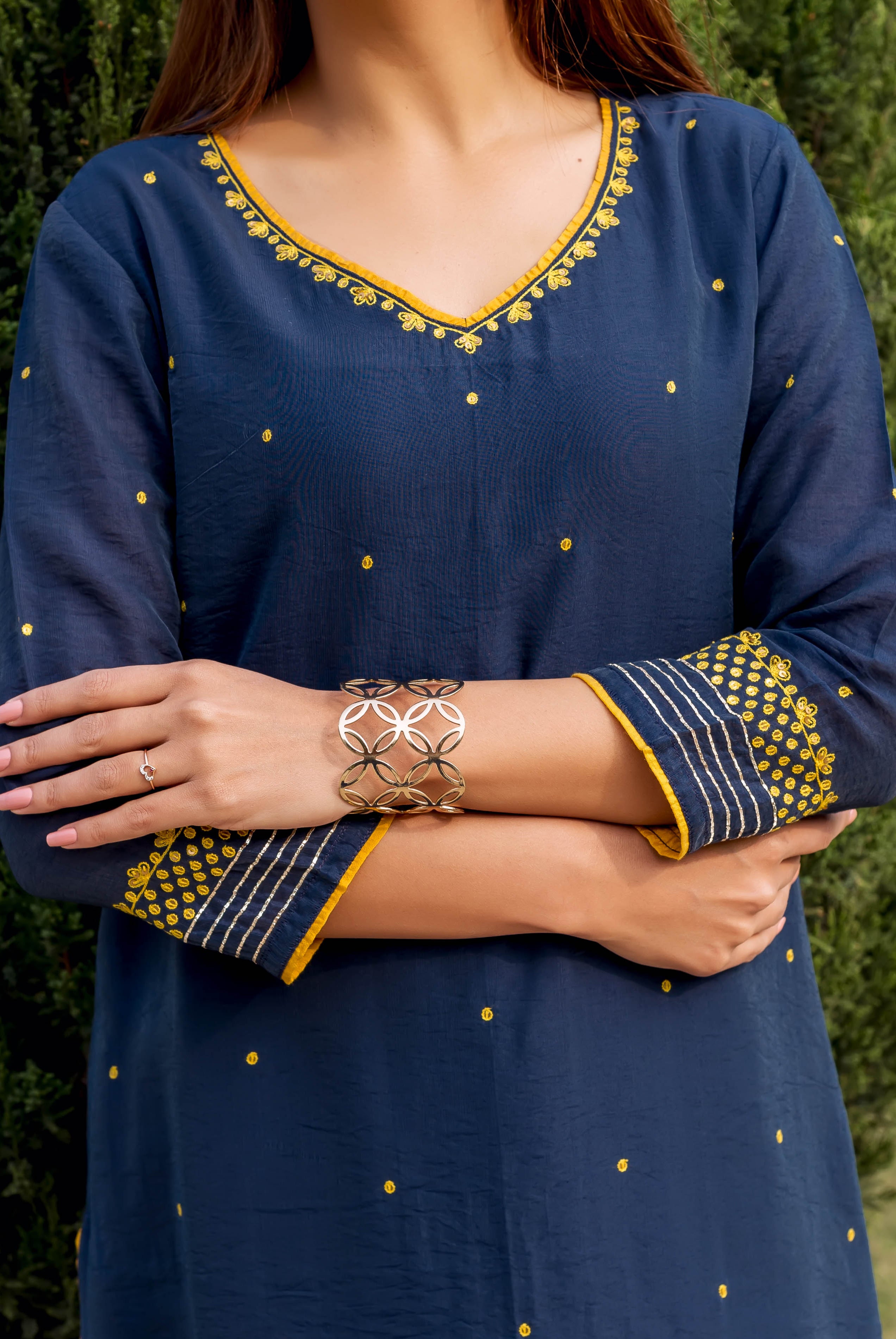 Navy blue kurta with yellow embroidered details and V-neckline, woman wearing gold bracelets.