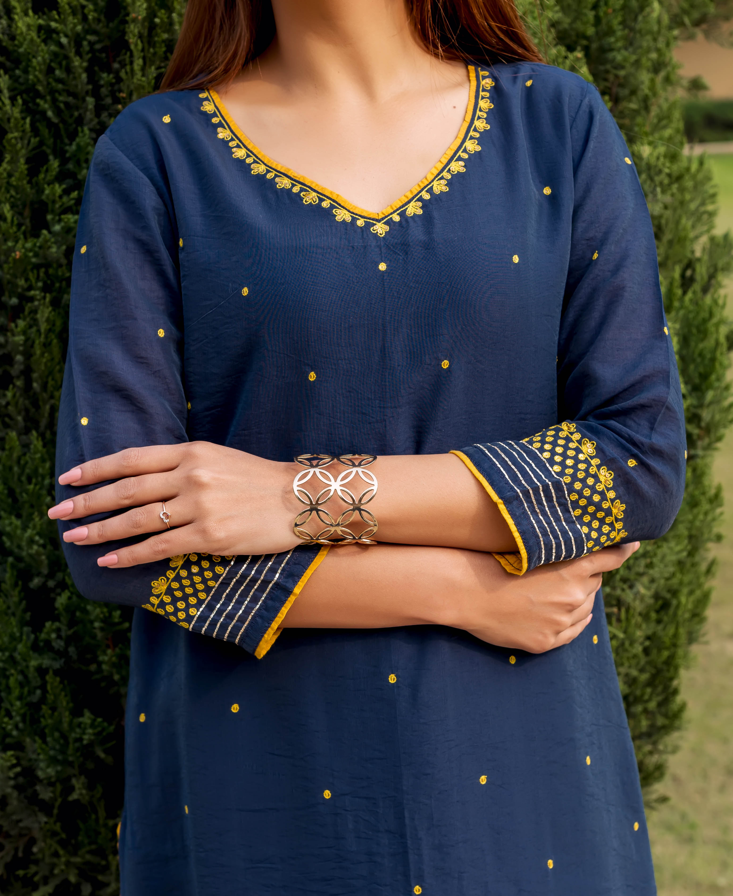 Navy blue kurta with yellow embroidered details and V-neckline, woman wearing gold bracelets.