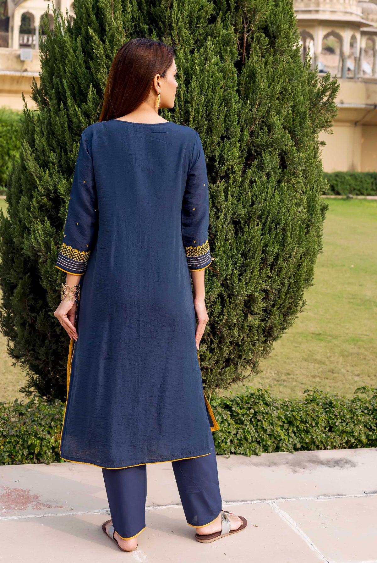 Model wearing navy blue kurta set, back view, with yellow embroidery and trim details.