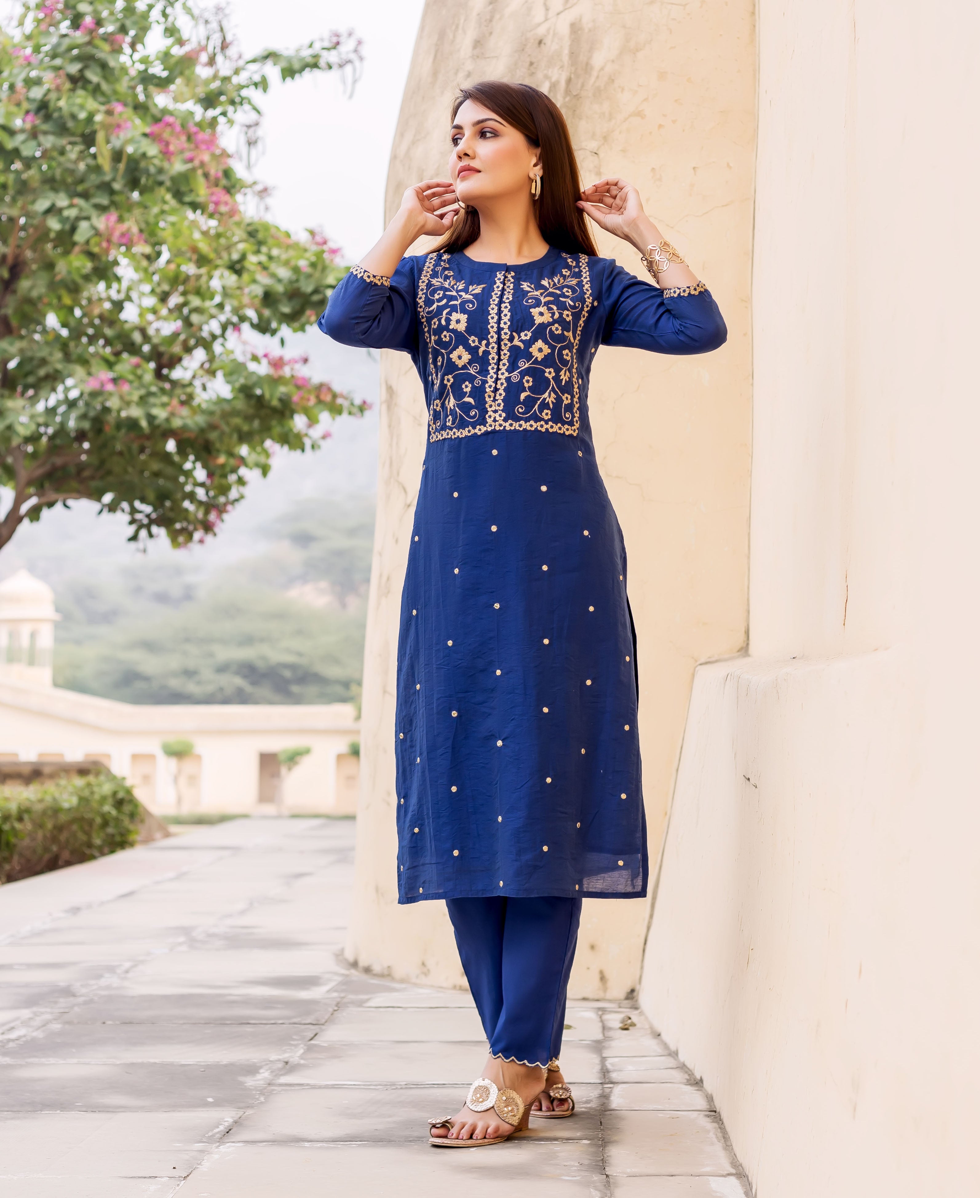 Full shot of model wearing a midnight blue hand-embroidered kurta set with gold patterns.