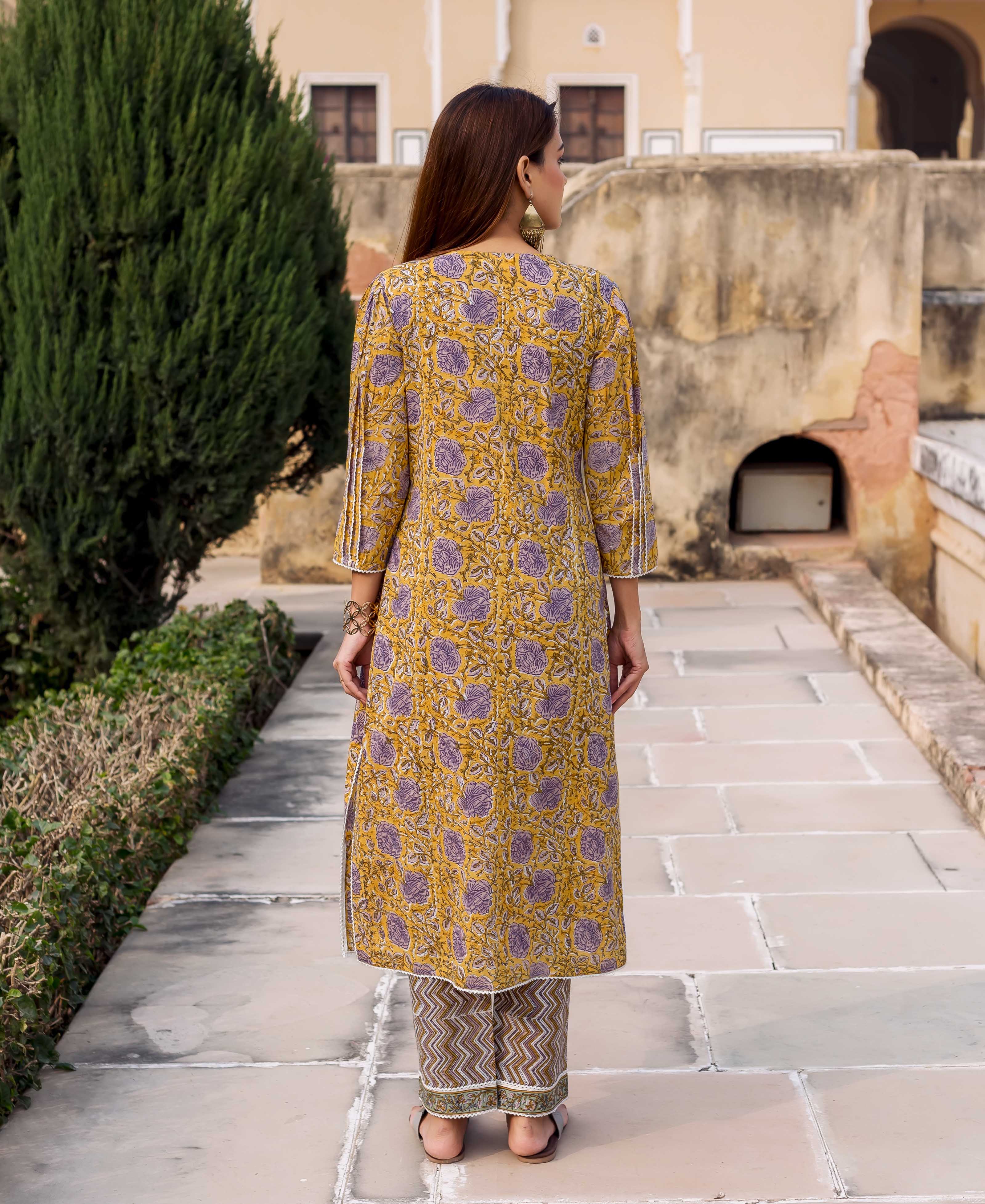 Woman from behind in yellow and purple floral hand block printed kurta with grey chevron pants.