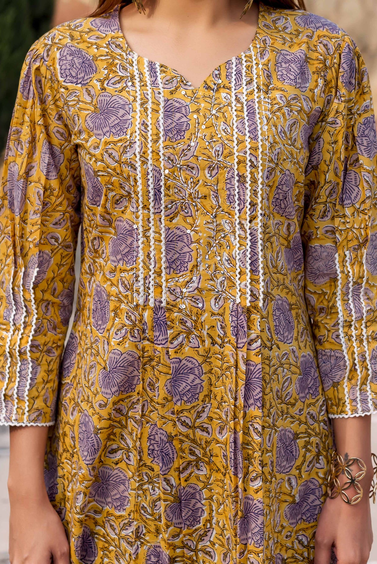 Front view of yellow and purple floral hand block printed kurti with white lace and pintucks.
