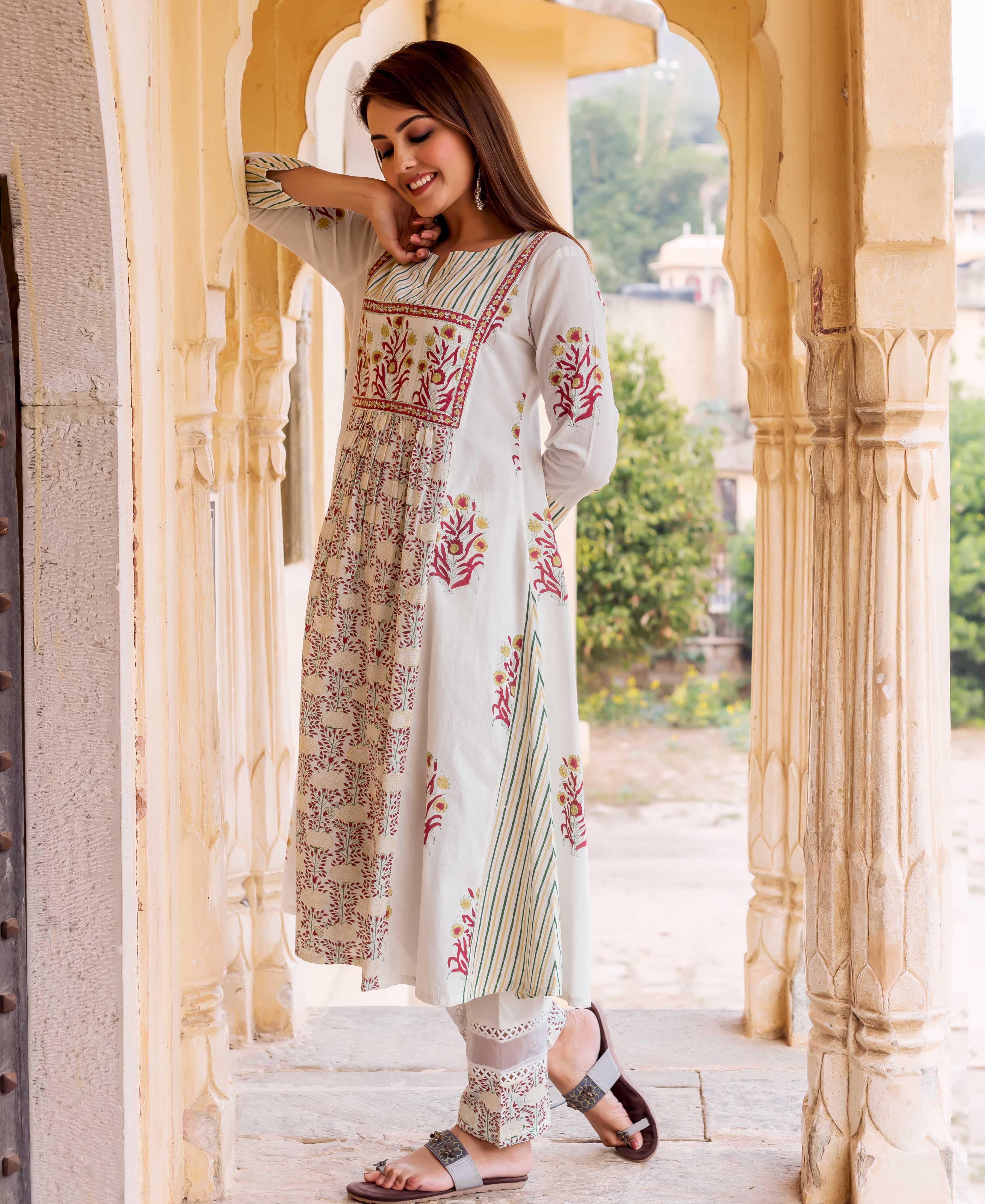 Smiling model in off-white hand block printed kurta with red floral and green striped patterns.
