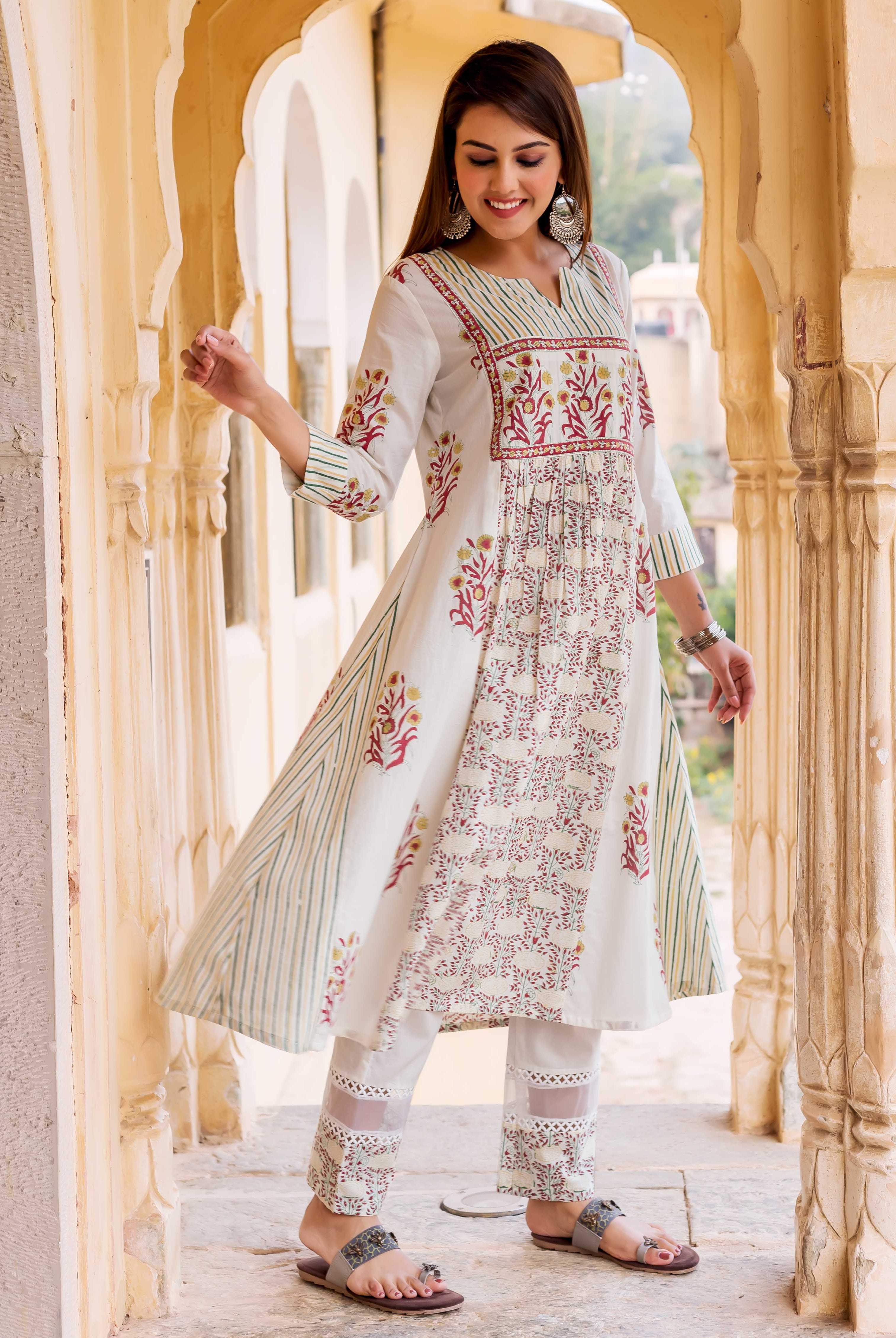Smiling model wears a white hand-block-printed kurta featuring red floral and green stripes.