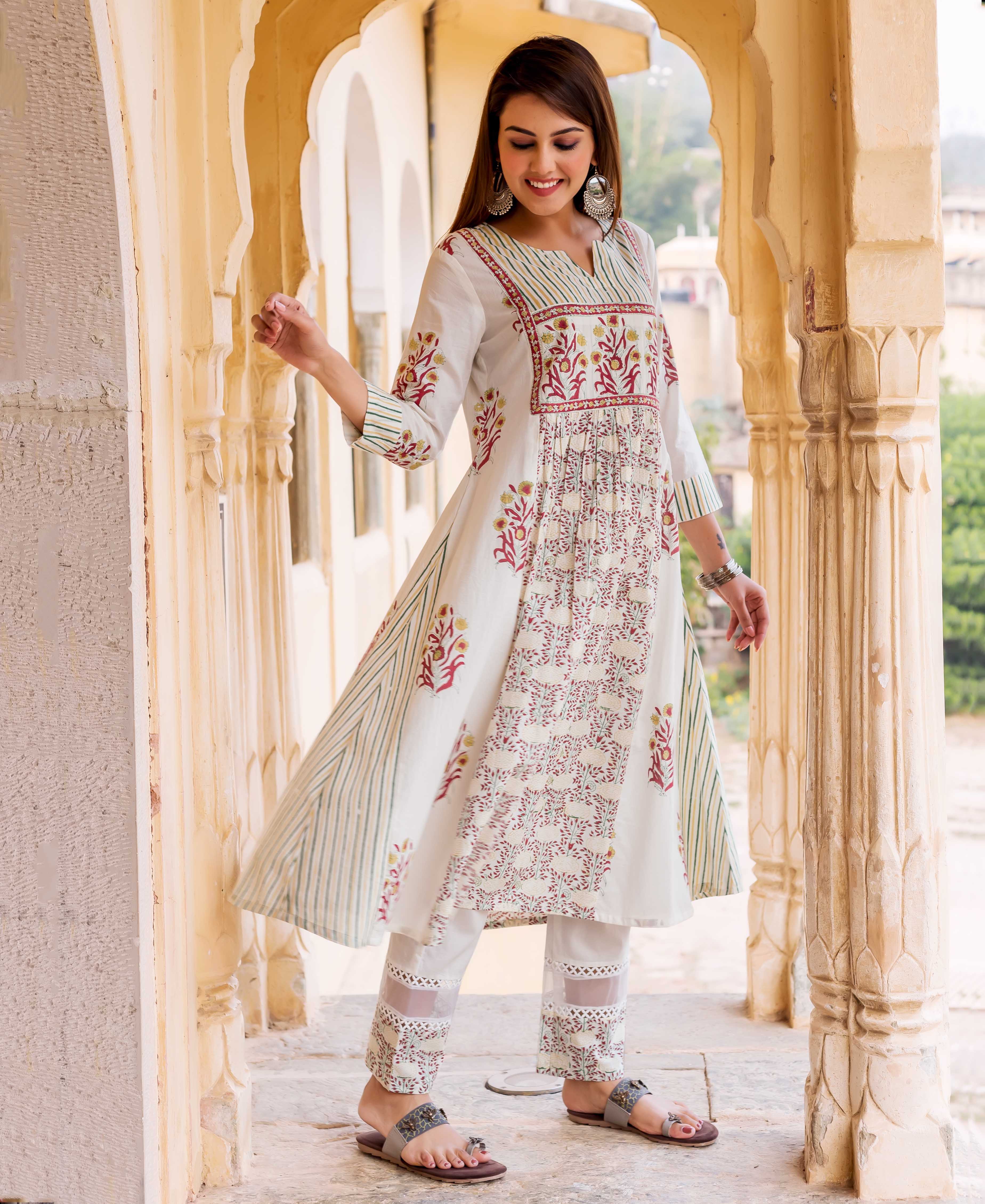 Smiling model wears a white hand-block-printed kurta featuring red floral and green stripes.