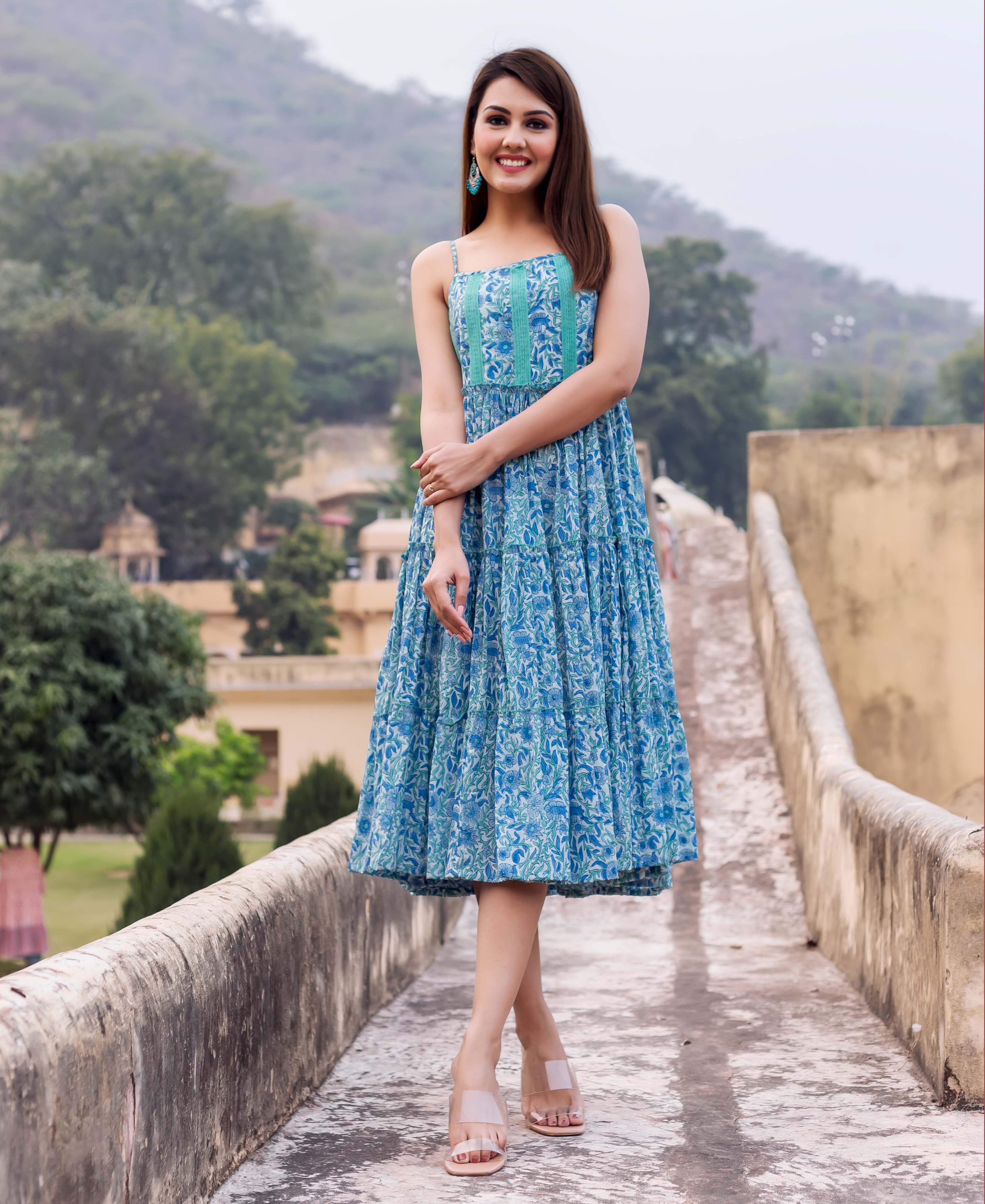 Smiling model in a full-body view wearing a blue and teal floral block print tiered sundress.