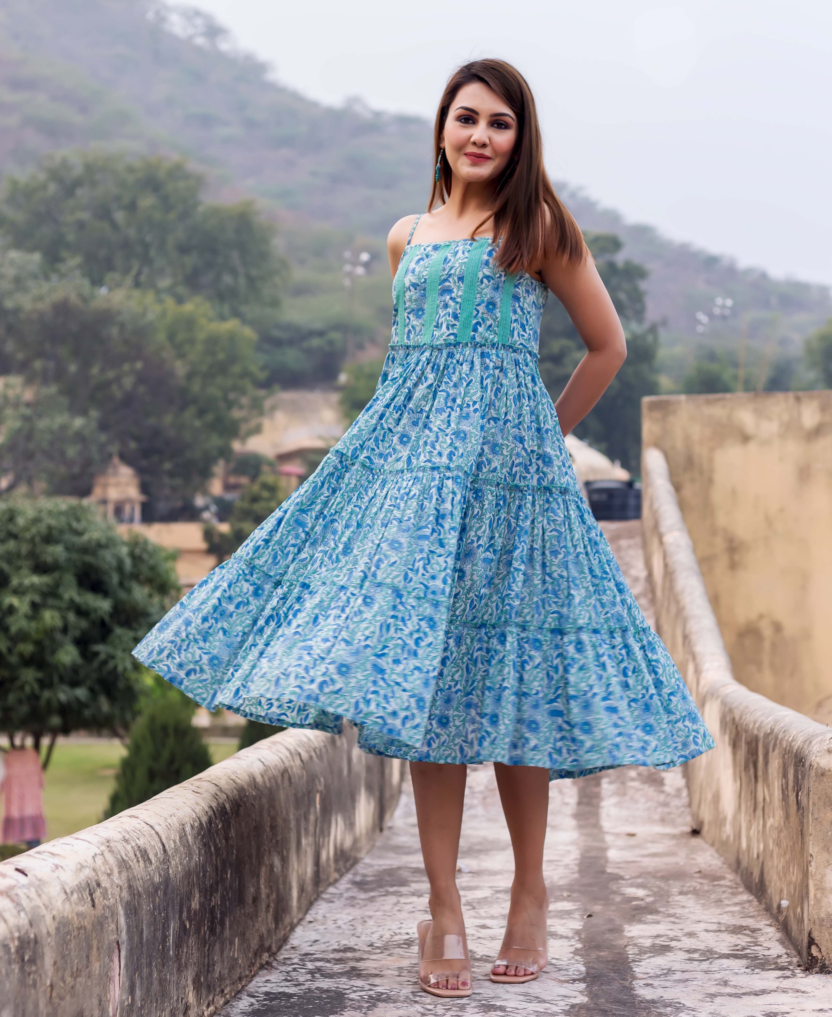 Model in a flowing blue floral hand block printed tiered sundress with spaghetti straps.