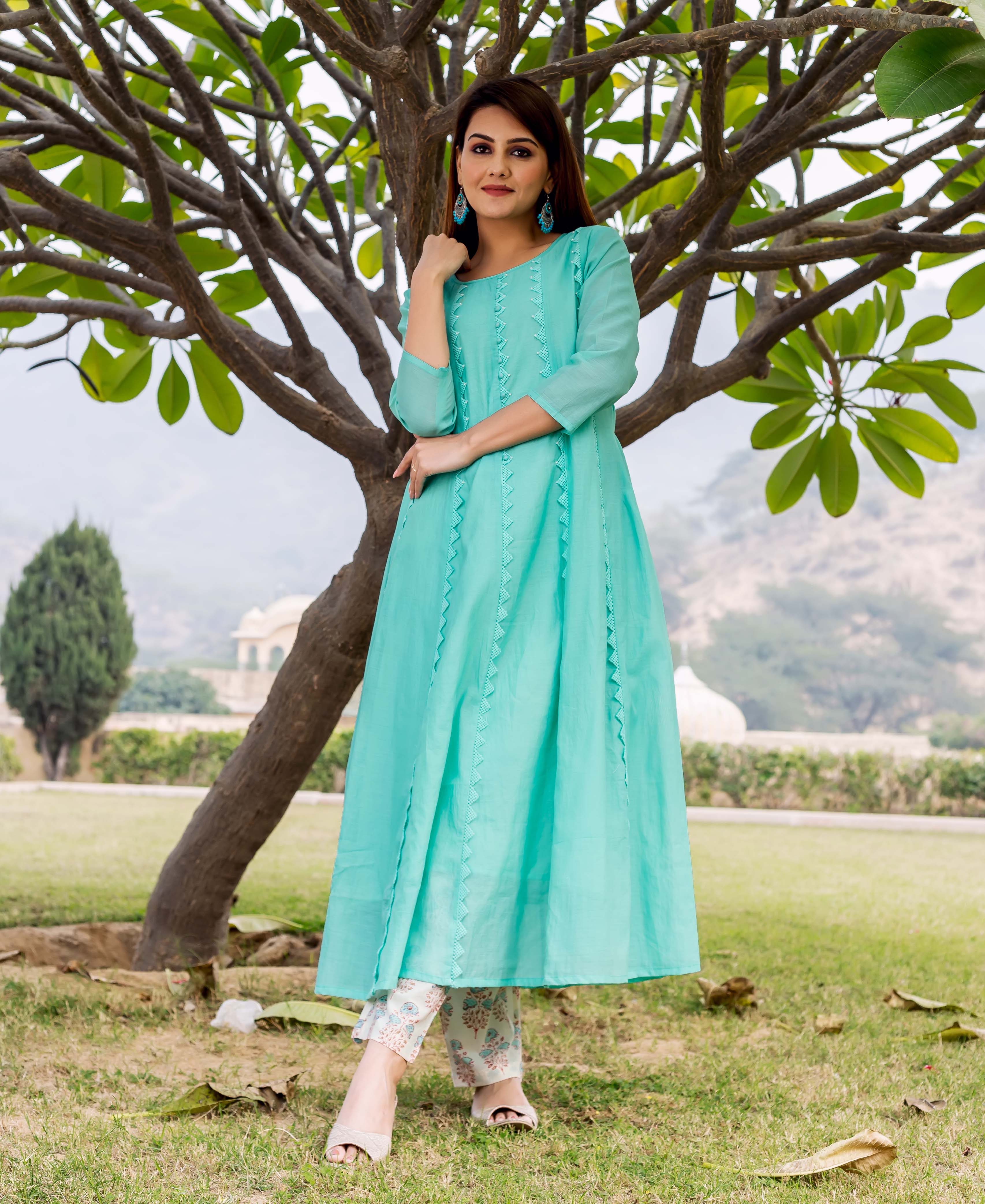 Sea green embroidered kurta with zigzag details on a model standing under a tree.
