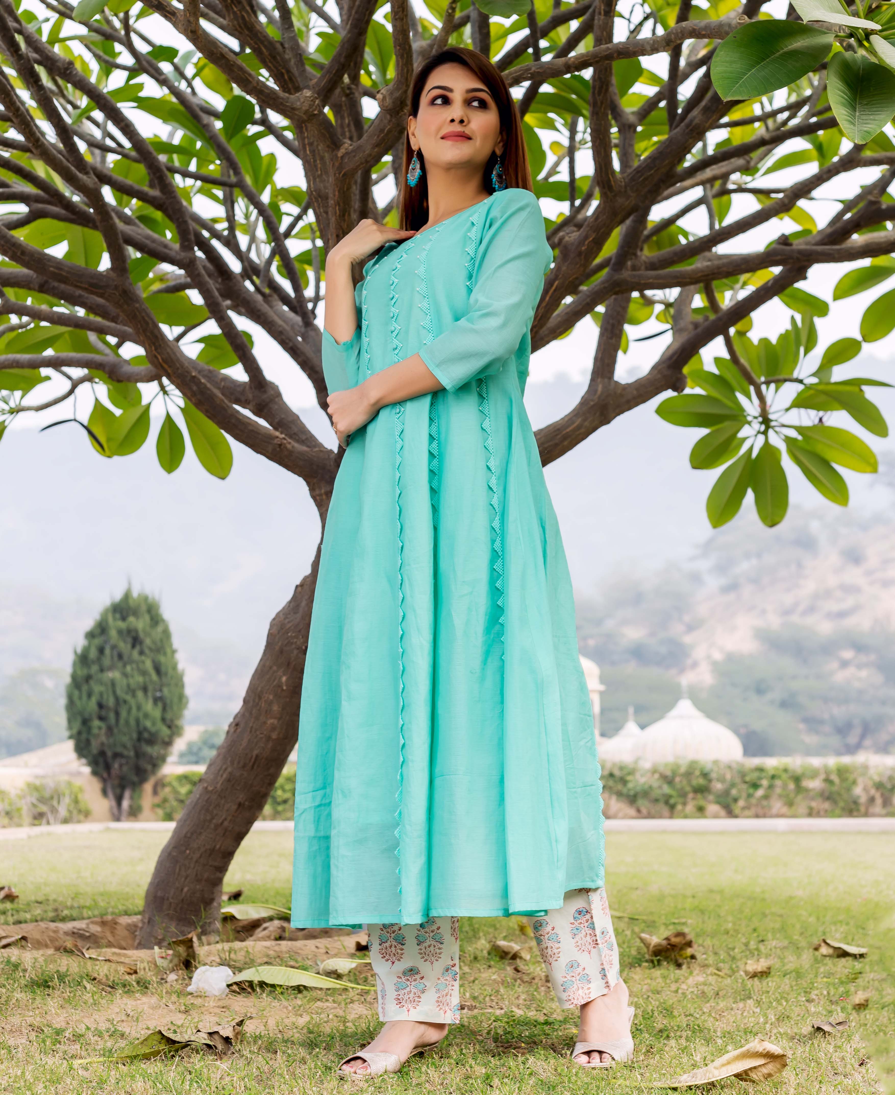 A model wearing a sea green chanderi kurta with embroidery, standing in front of a tree.