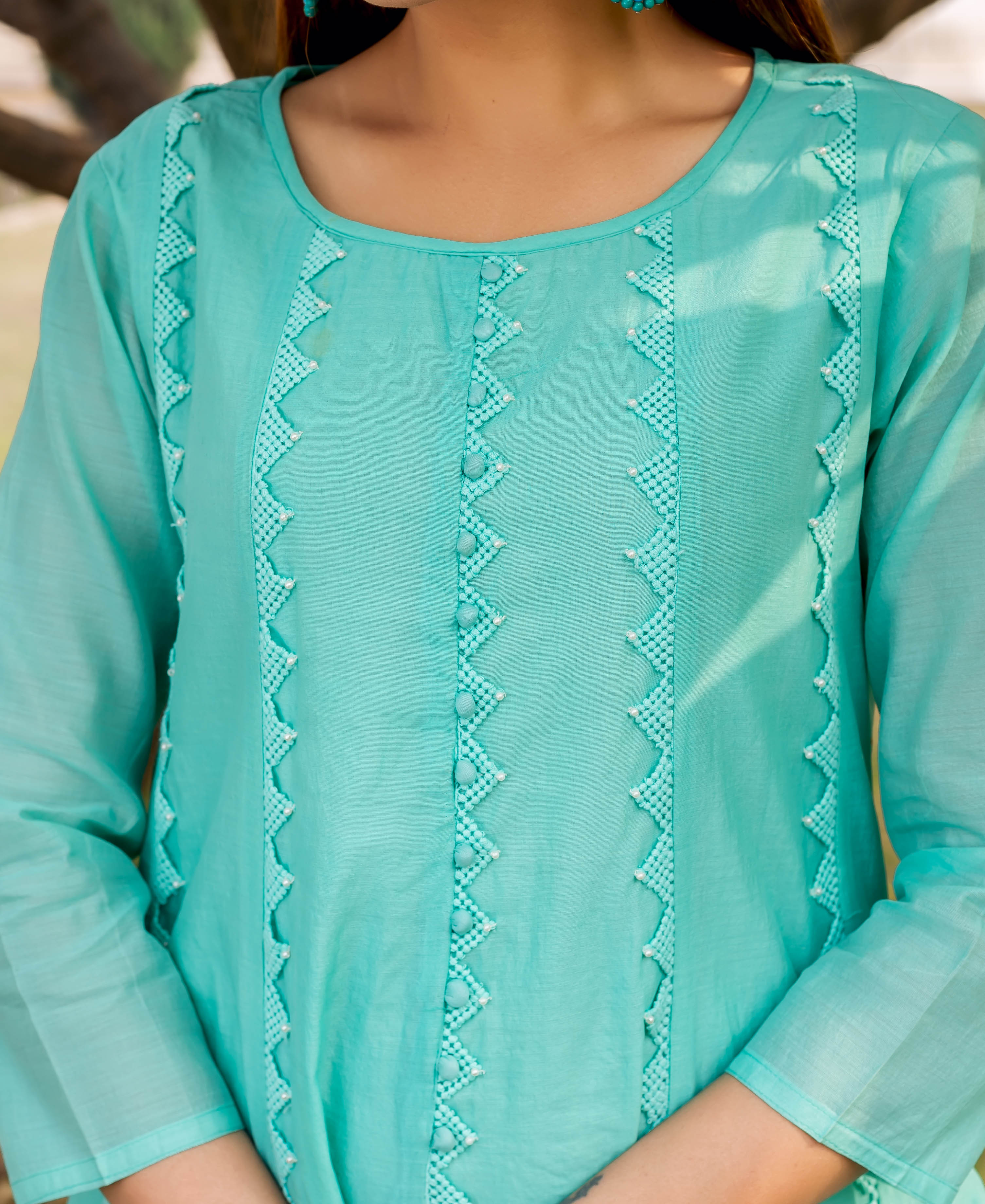 Front view, model wearing a sea green kurta with intricate vertical beaded zig-zag embroidery.