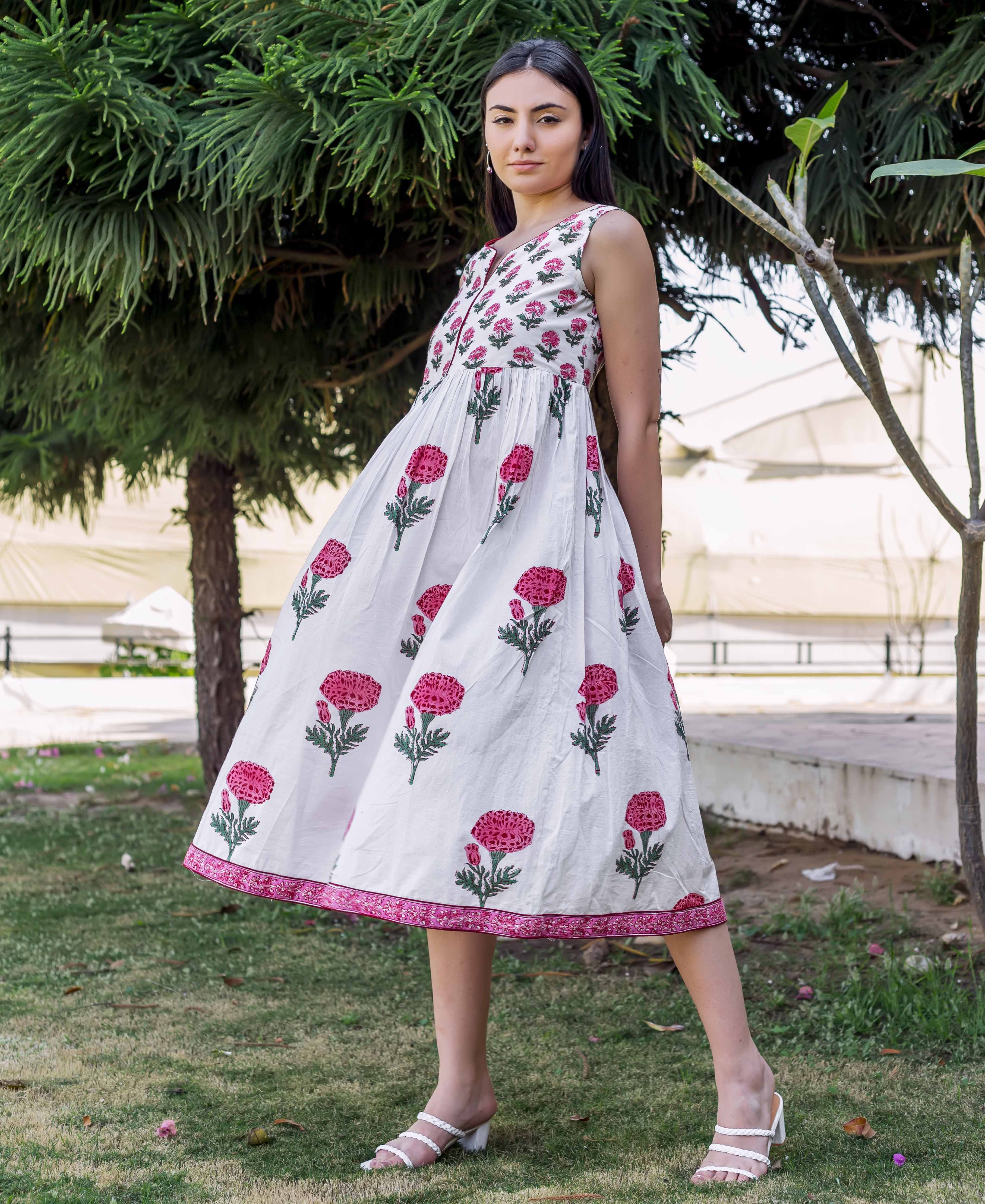 Woman in white sleeveless midi dress with pink marigold hand block print.