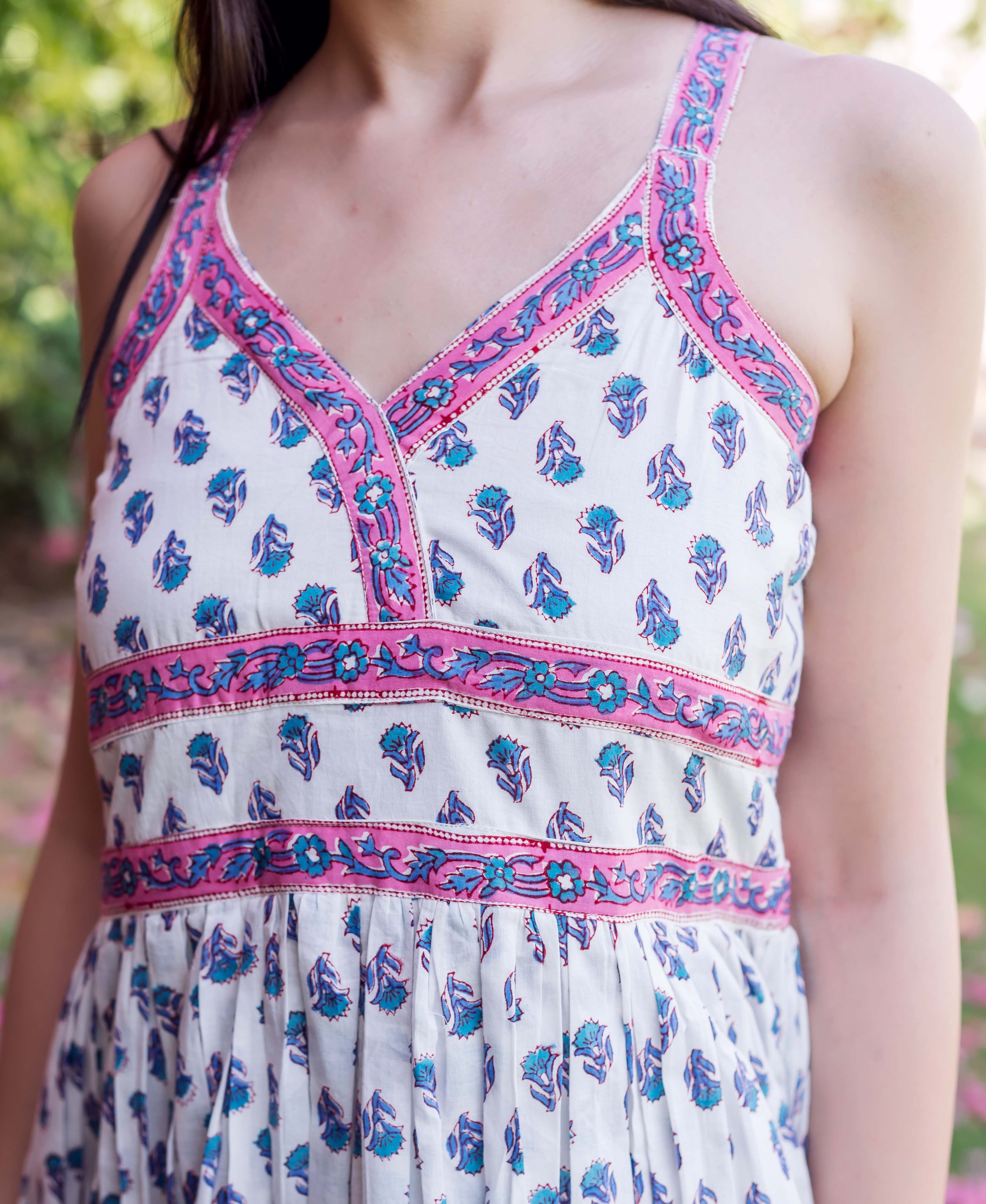 Model wearing a white sleeveless V-neck dress with pink and blue floral block print.
