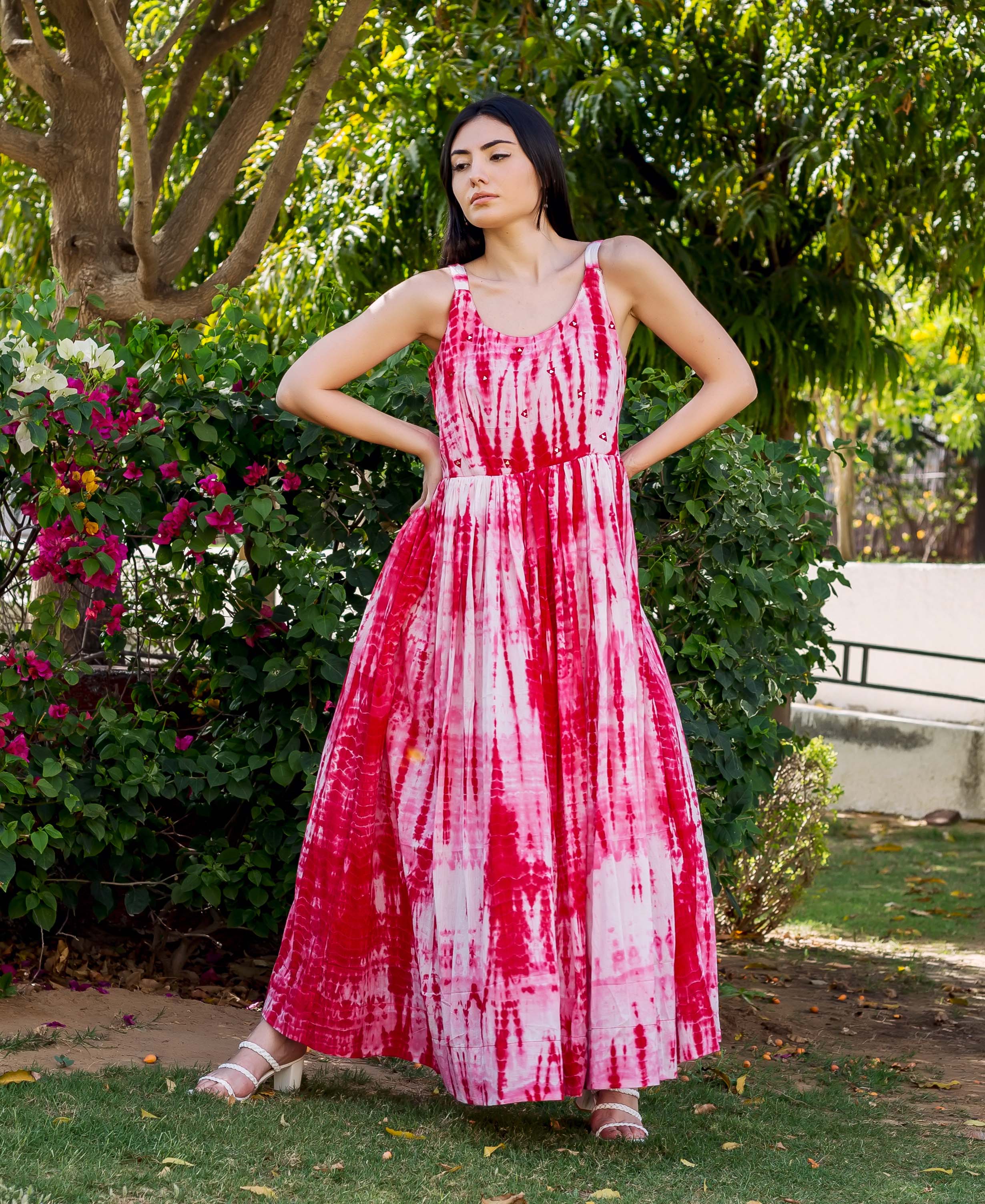Full body shot of a woman wearing a red and white tie-dye embroidered sleeveless maxi dress.