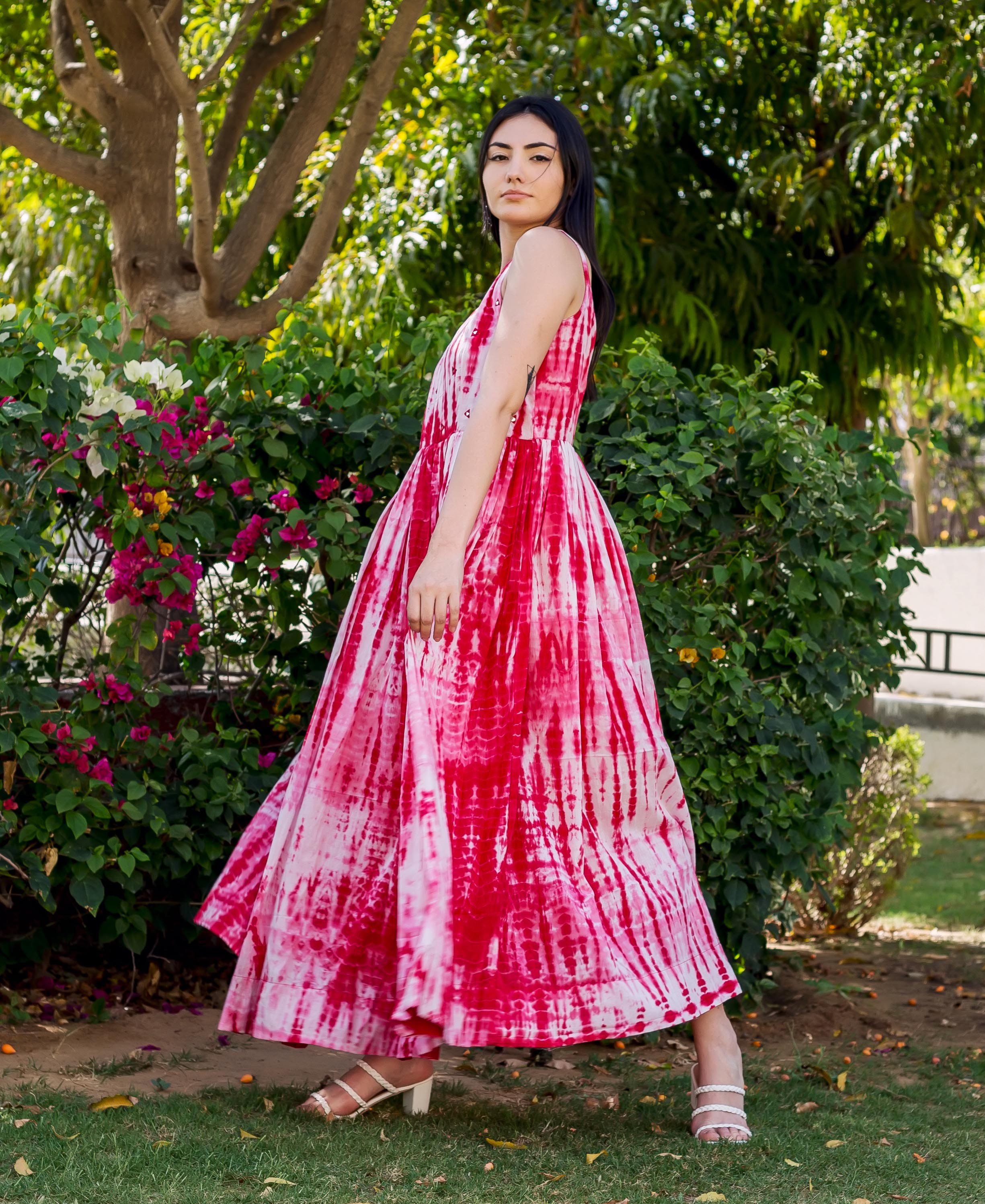 Model wears a flowing red and white tie-dye sleeveless maxi dress outdoors.