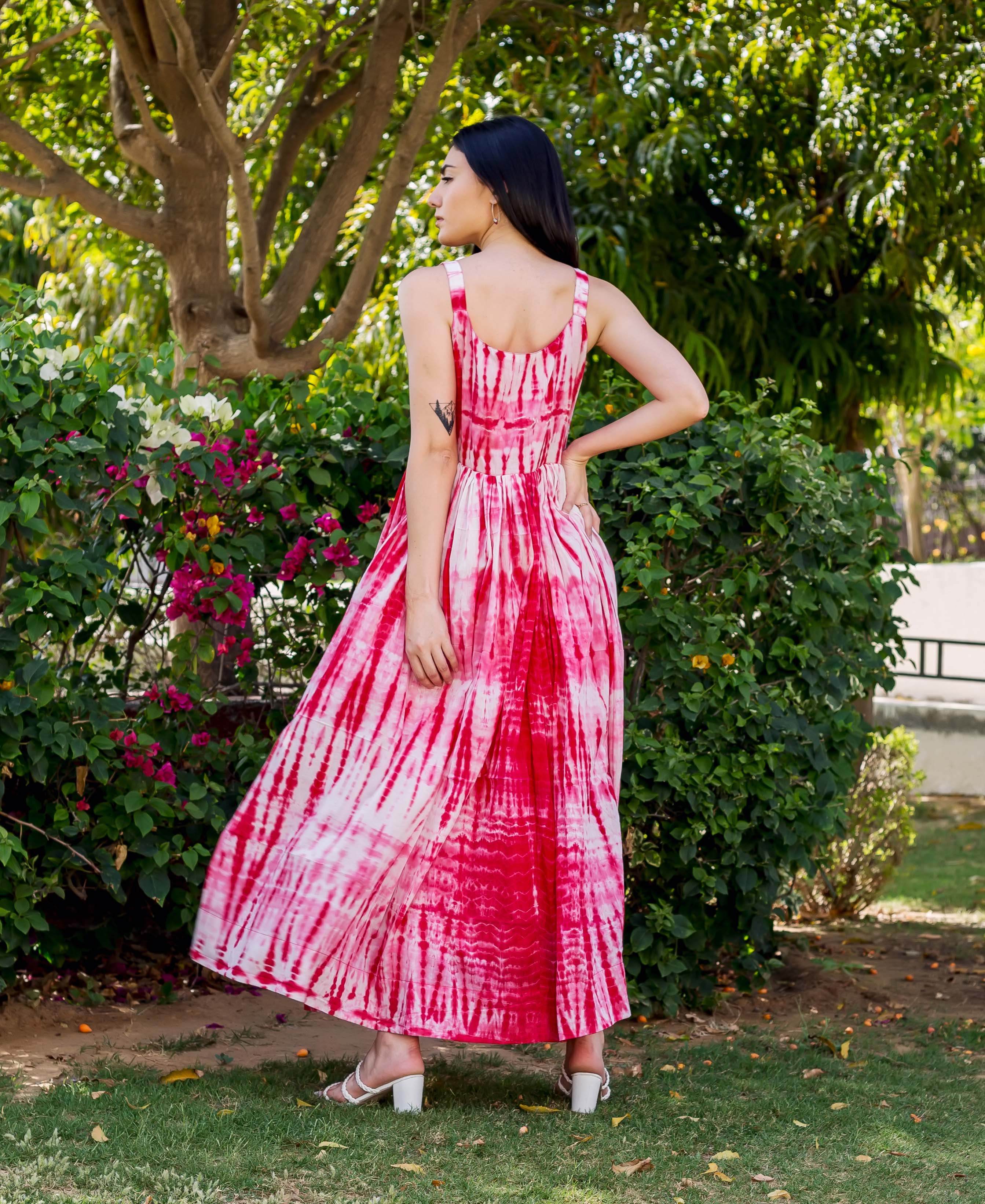 Model in a vibrant red and white tie-dye flowing sleeveless maxi dress, seen from behind.