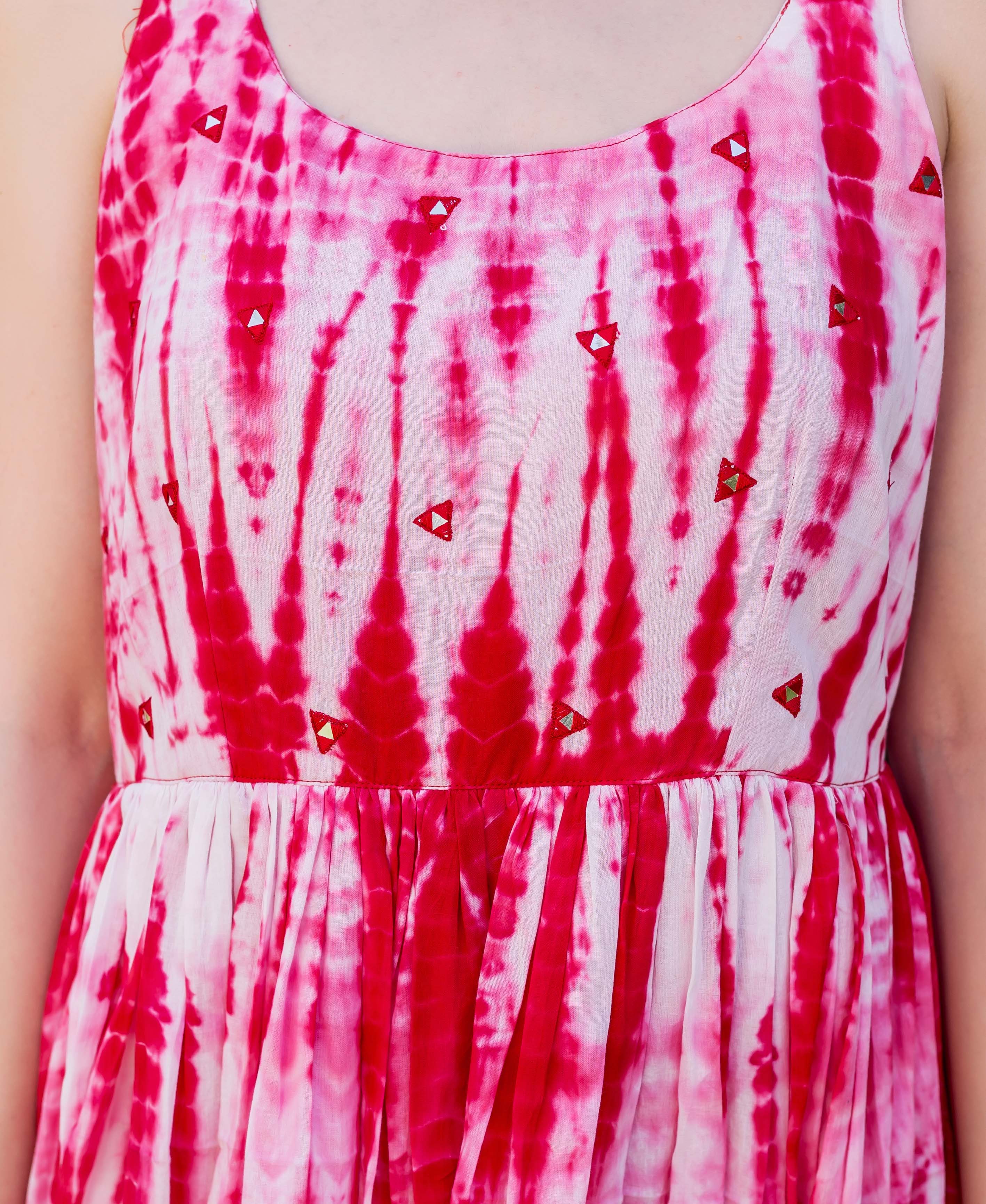 Close-up of a red and white tie-dye dress with triangular embroidery on a model.