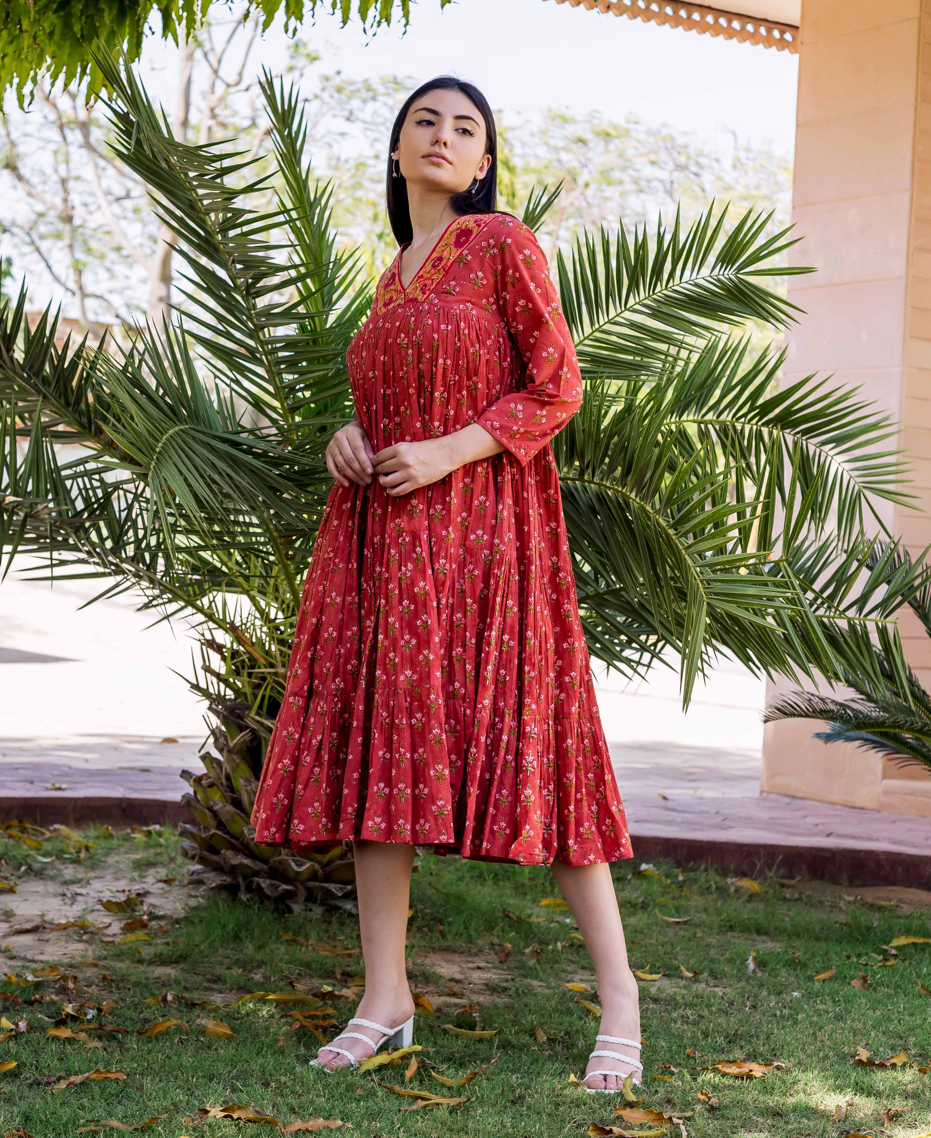 Model in a maroon hand-block-printed tiered dress with delicate floral patterns and an embroidered V-neck.