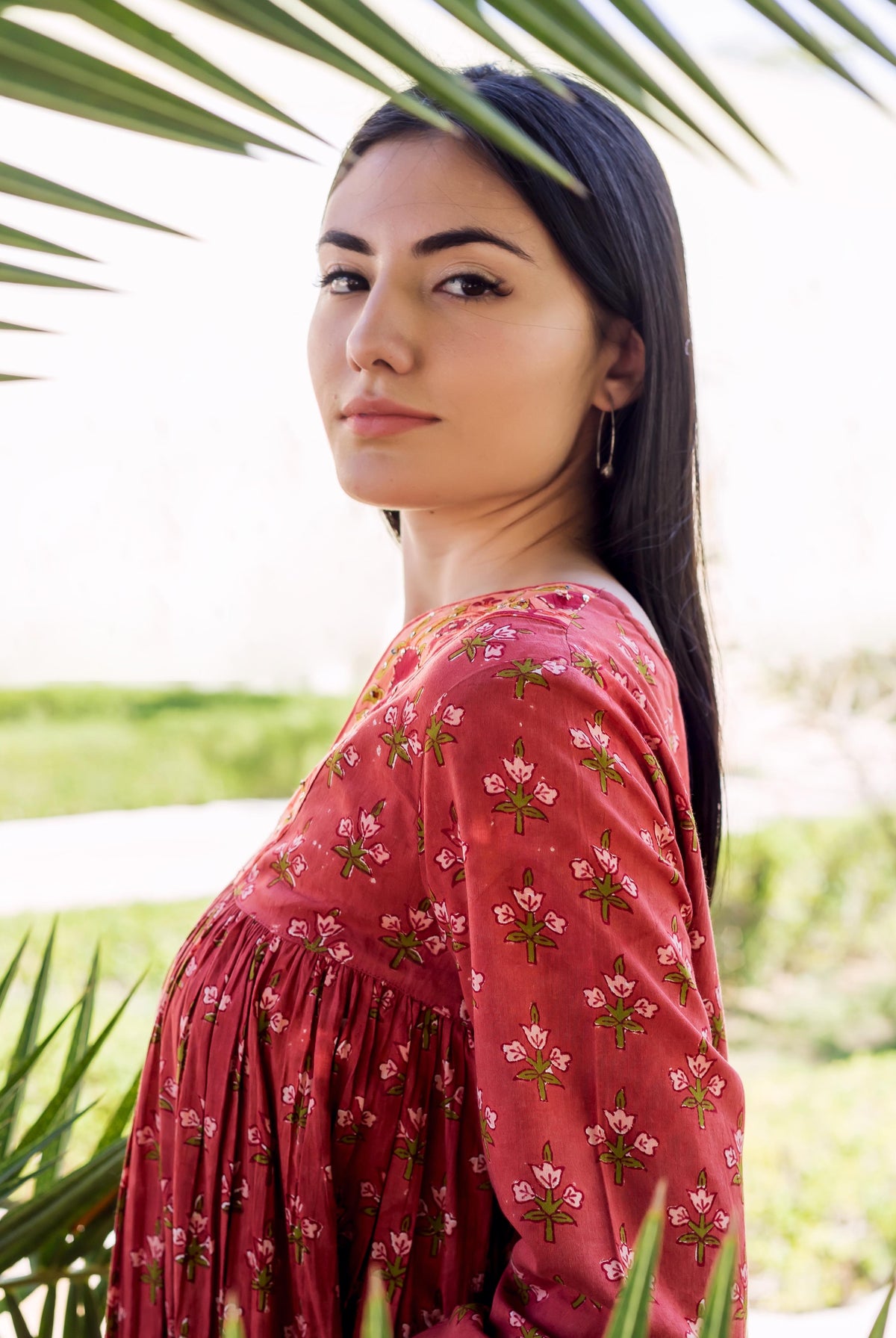 Model in a maroon tiered long-sleeved dress with green and white floral block print.