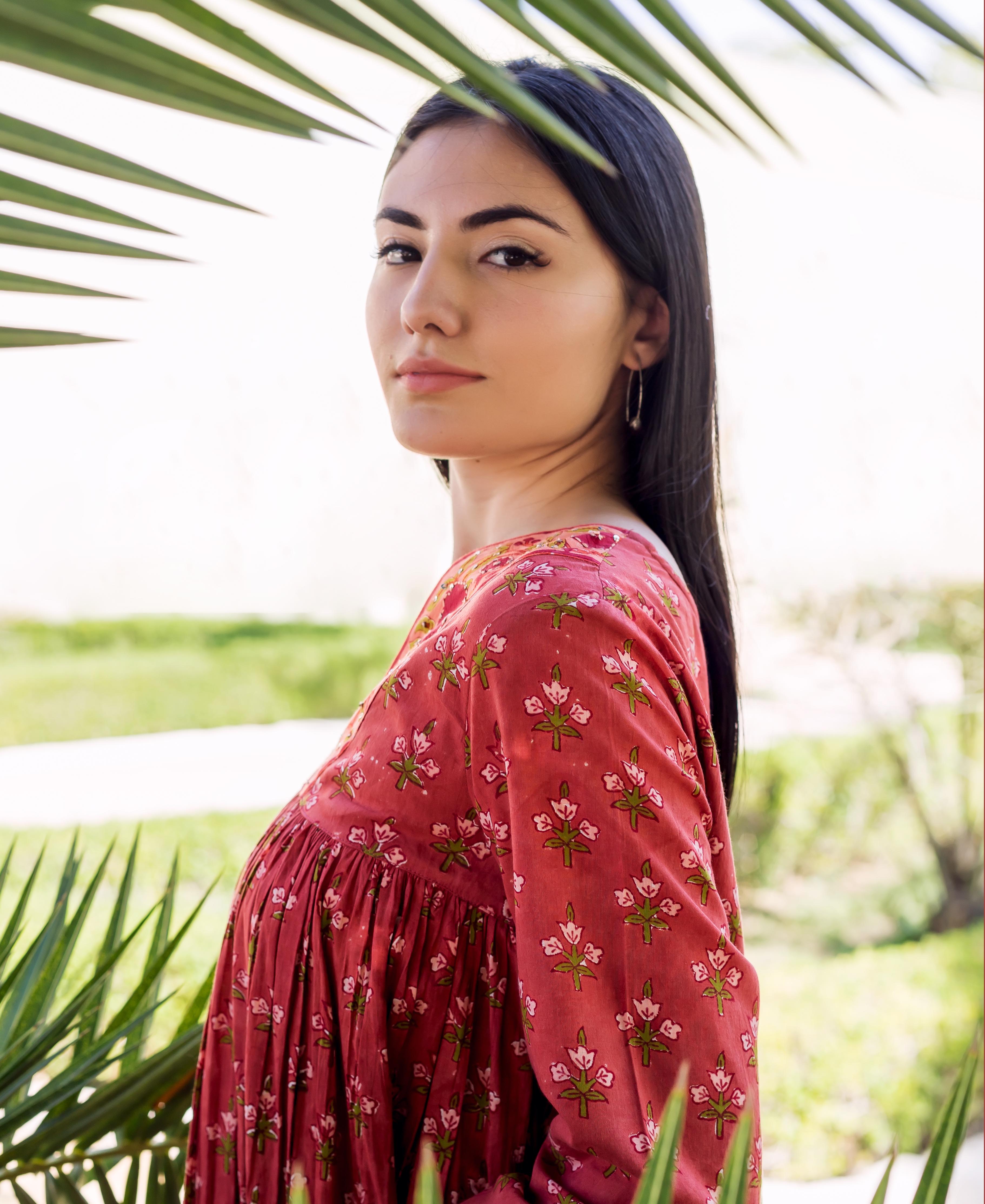 Model in a maroon tiered long-sleeved dress with green and white floral block print.