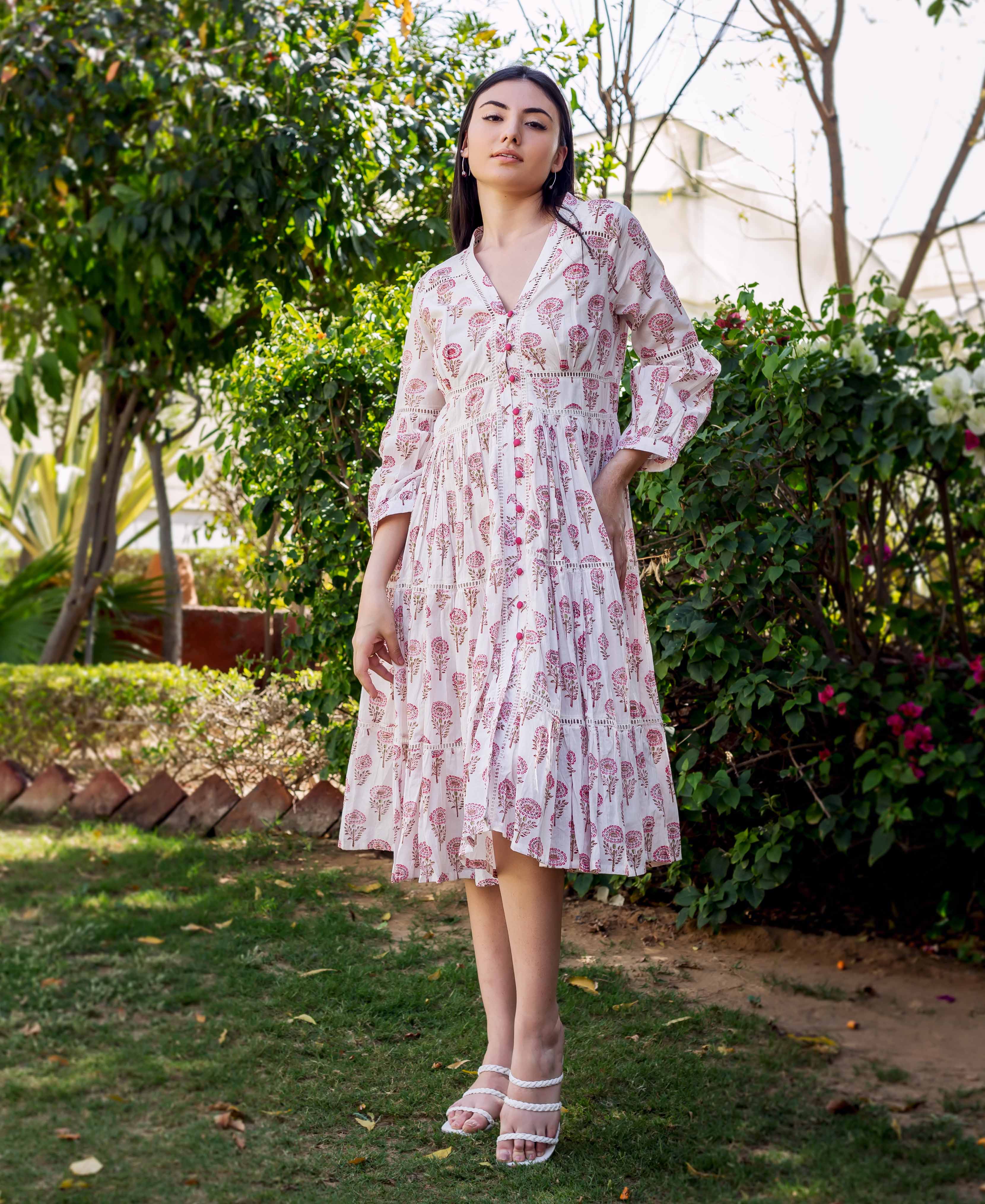 Full-length model wearing white and pink block printed tiered dress with lace trim.