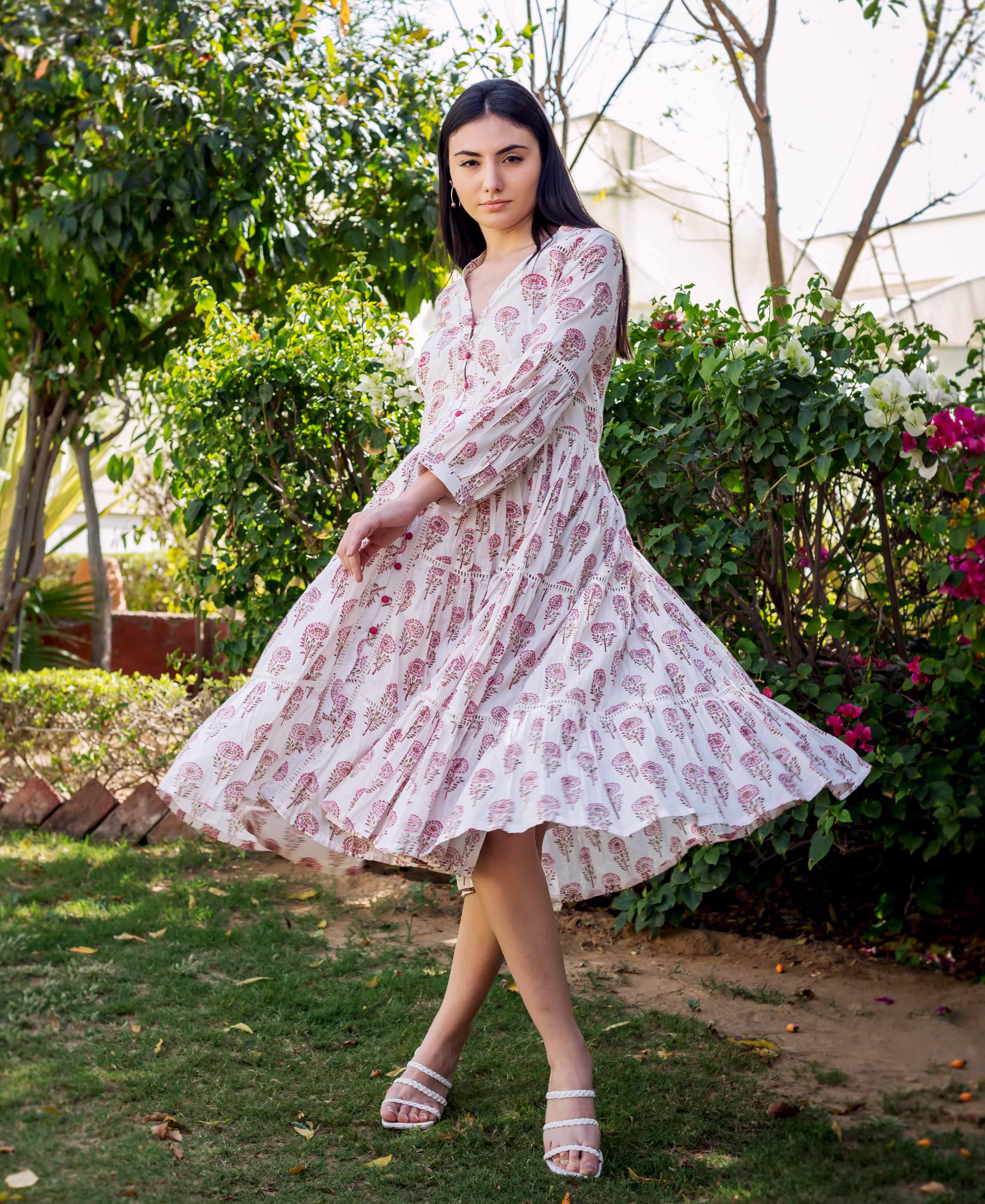 Model twirling in a white and pink ethnic block printed tiered dress with lace.