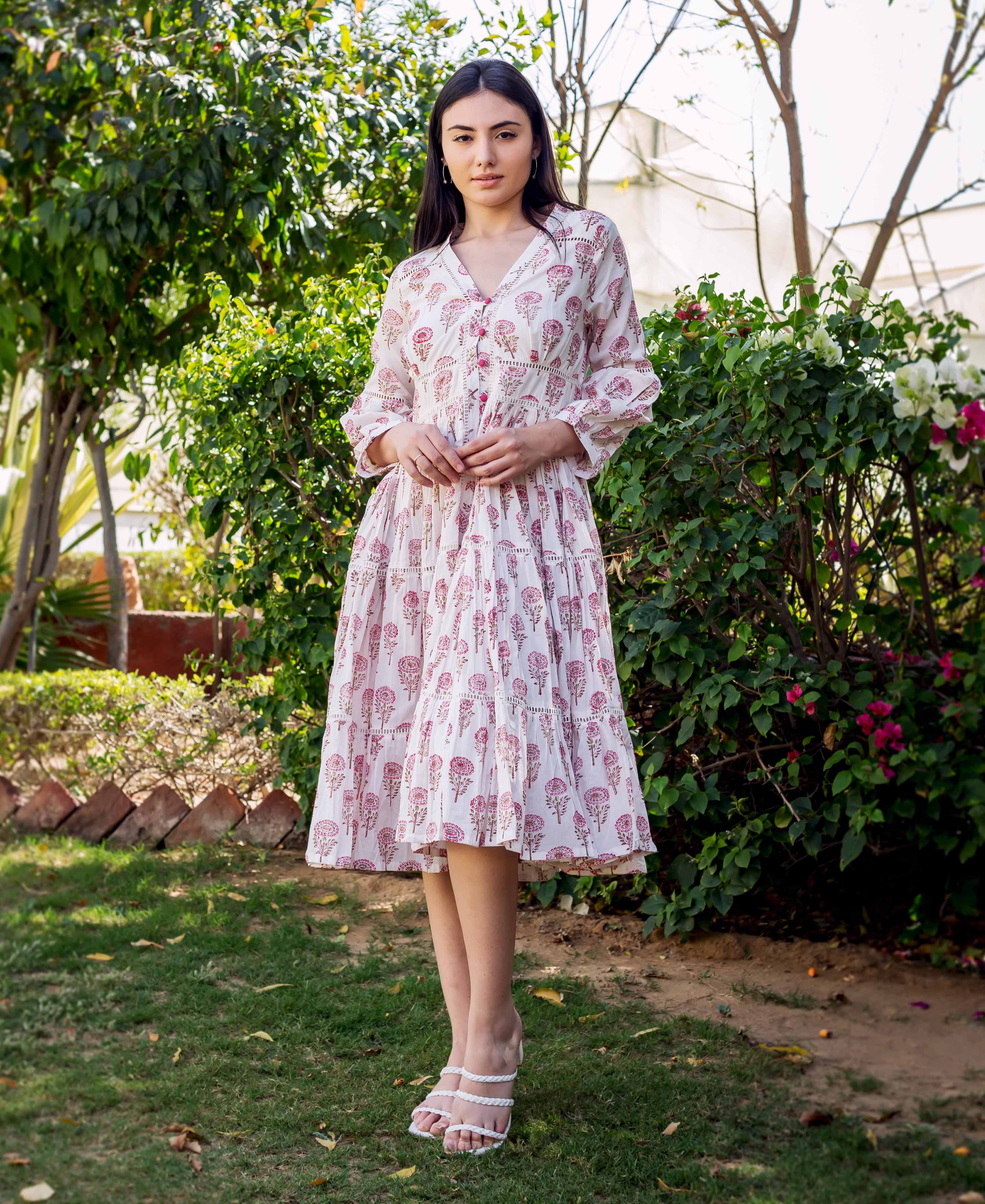 White and pink block printed tiered dress with floral pattern and lace trim on a model.