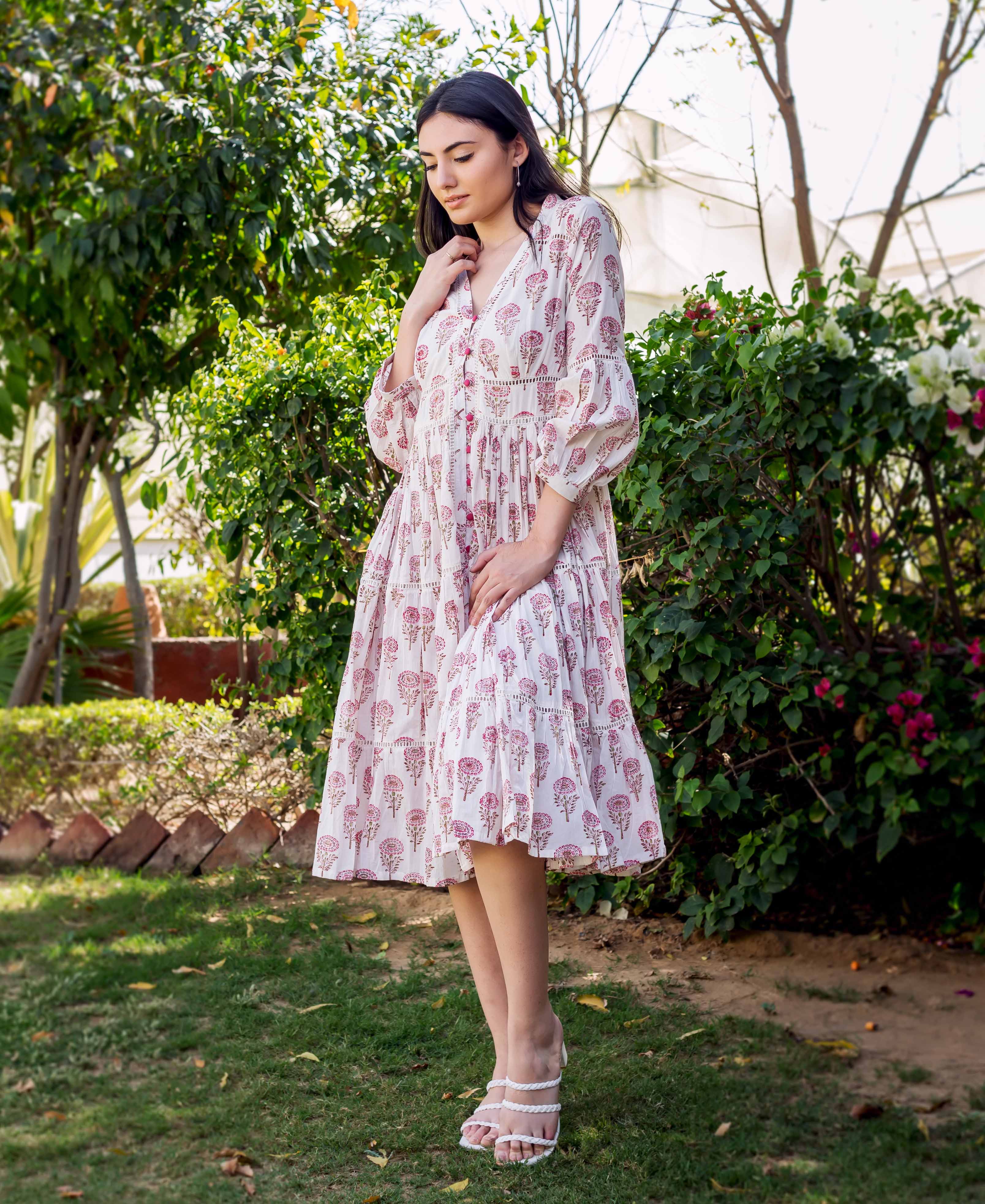 Model wearing a white and pink block printed tiered dress with lace details.