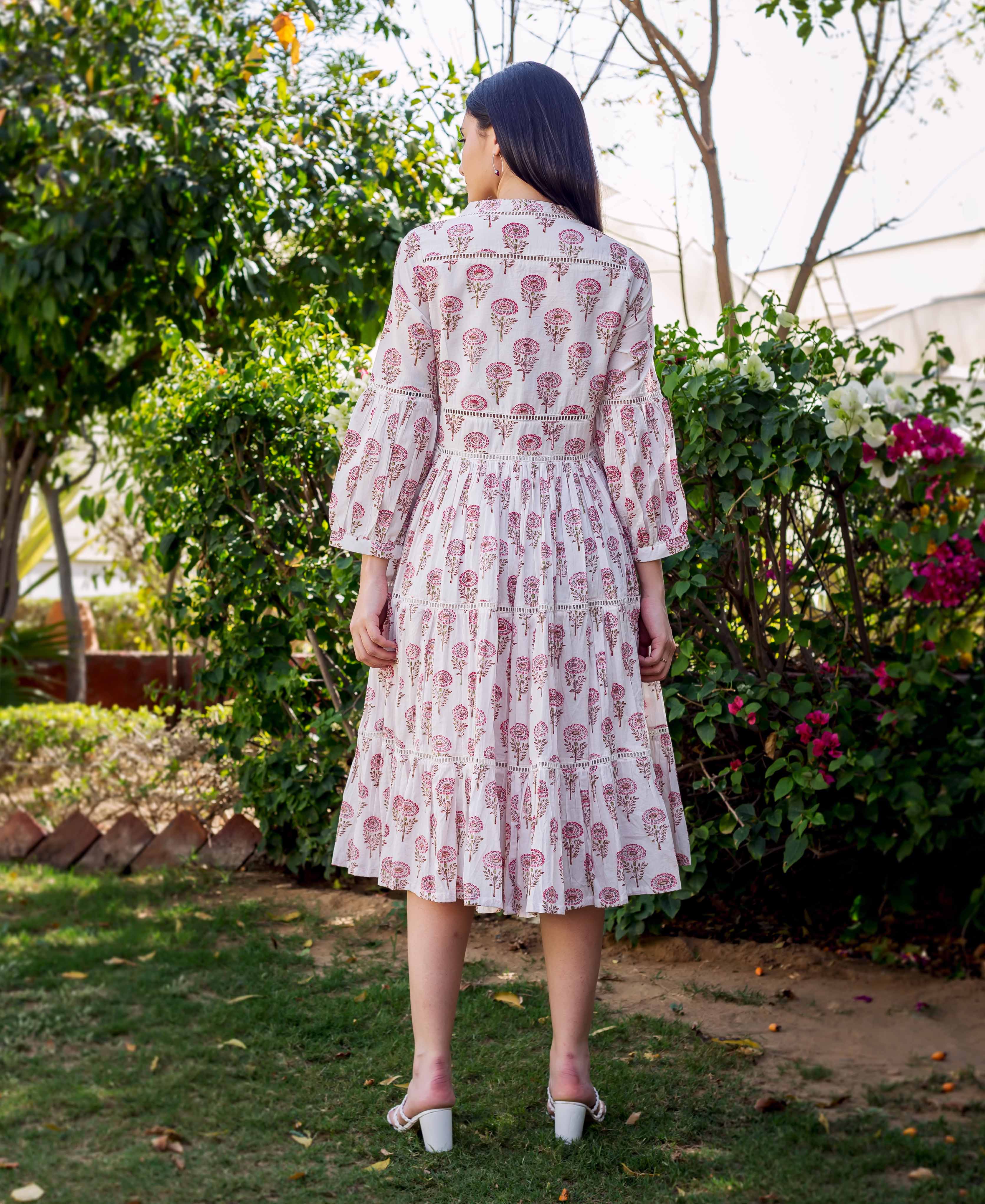 Back view of model in white and pink block-printed tiered dress with lace details.