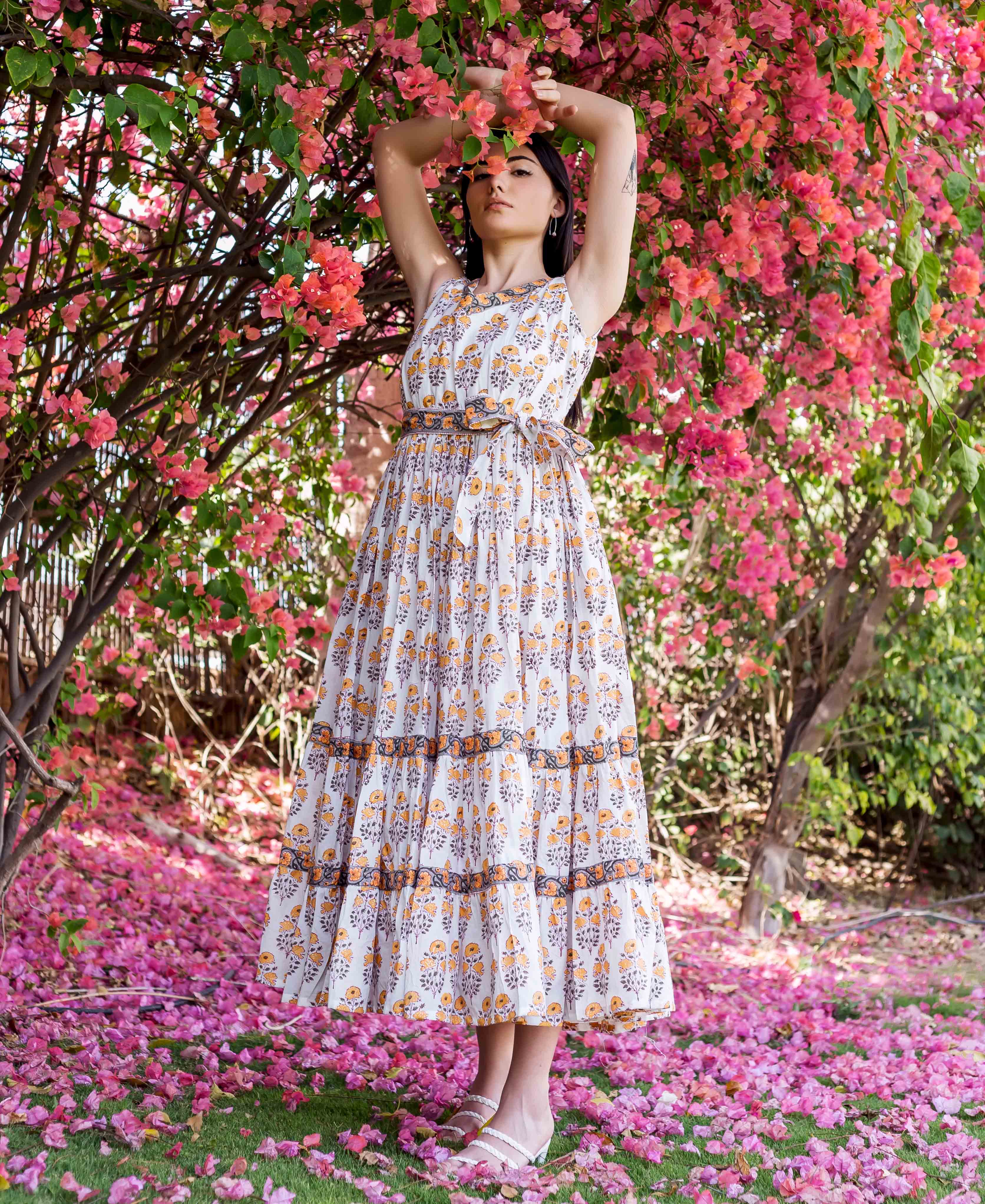 Full-body model wearing a white and yellow hand-block-printed floral tiered maxi dress.