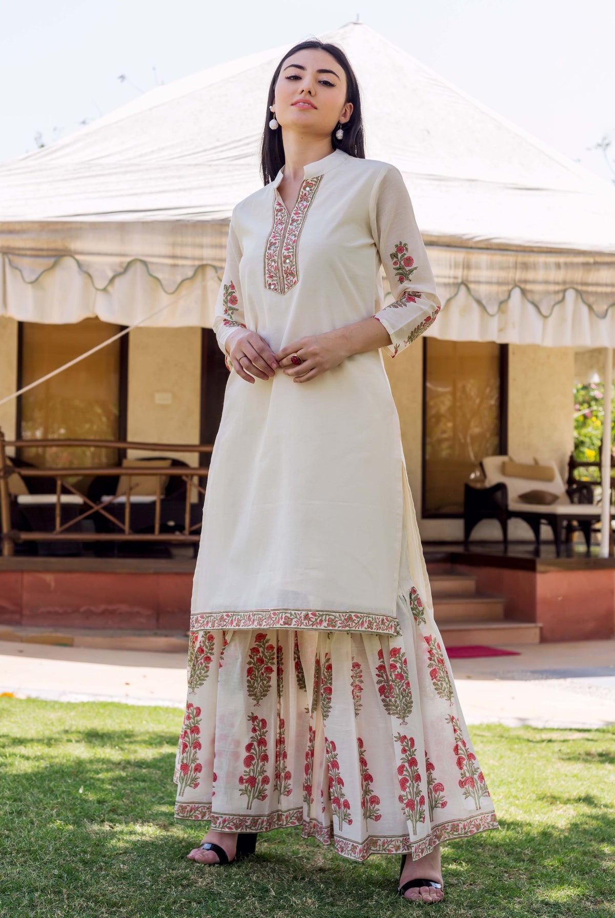 Model wears ivory embroidered kurta with floral block printed sleeves and matching sharara.