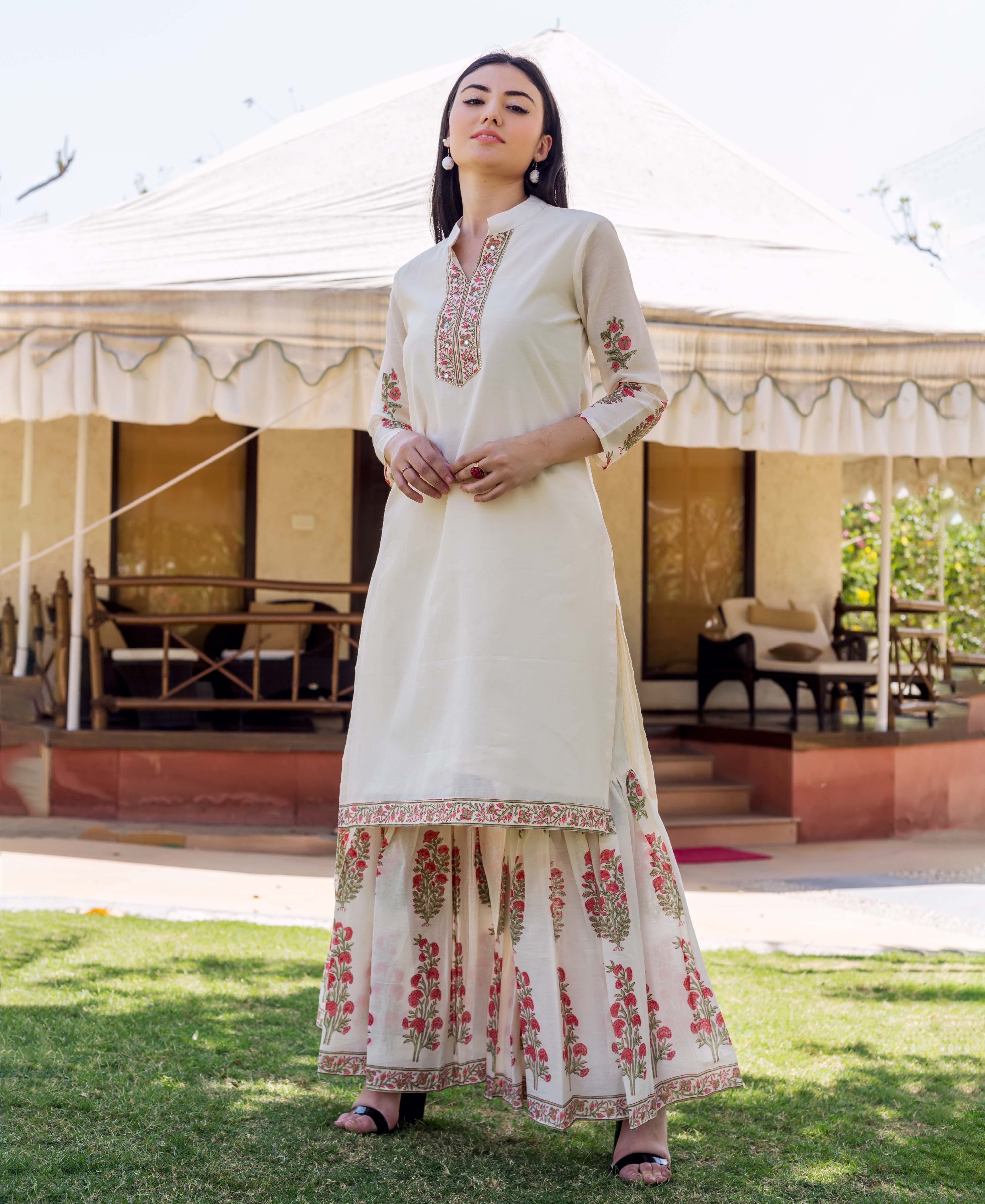 Model wears ivory embroidered kurta with floral block printed sleeves and matching sharara.