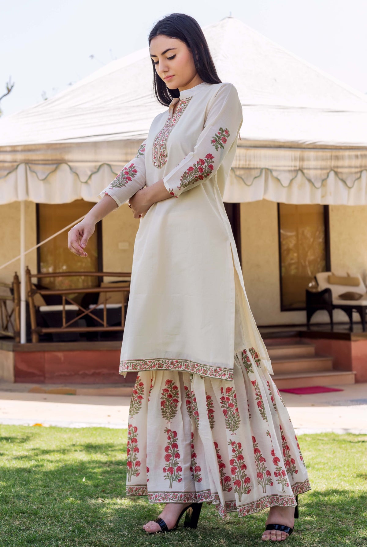 Model wears ivory kurta with embroidered neckline, floral block printed sleeves and sharara.