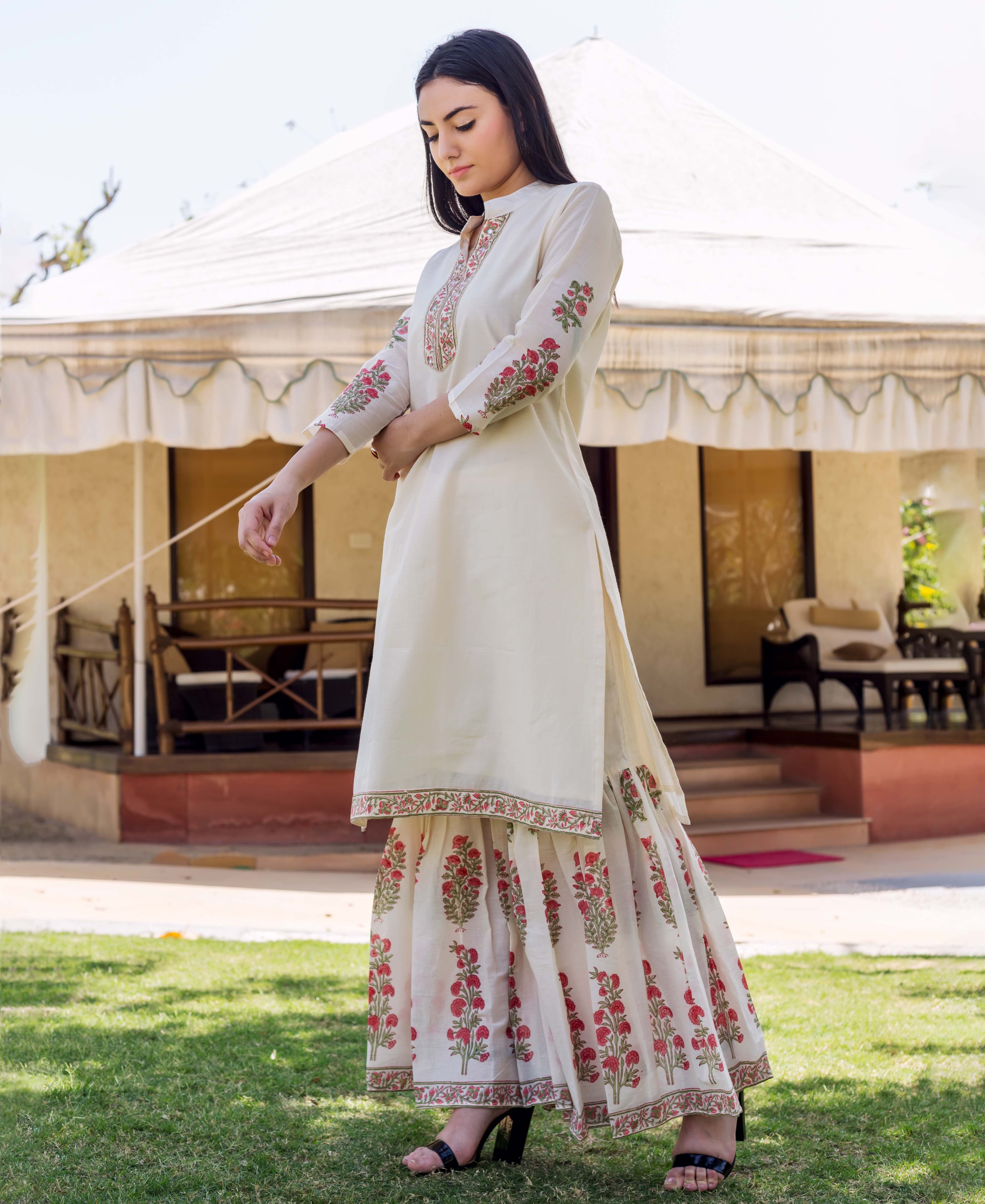 Model wears ivory kurta with embroidered neckline, floral block printed sleeves and sharara.