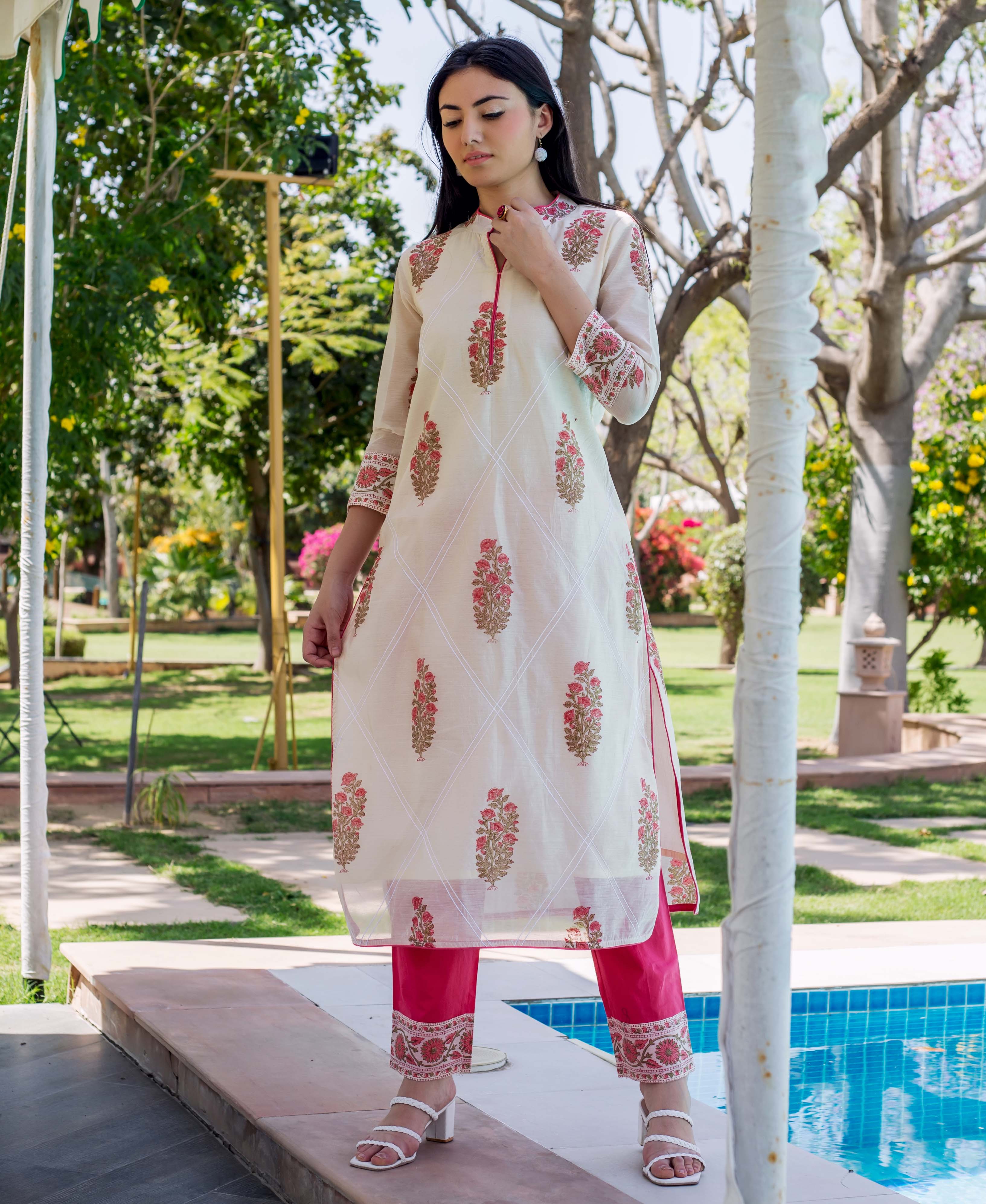 Model wears cream hand-block-printed straight kurta, fuchsia pants, and white braided heels.