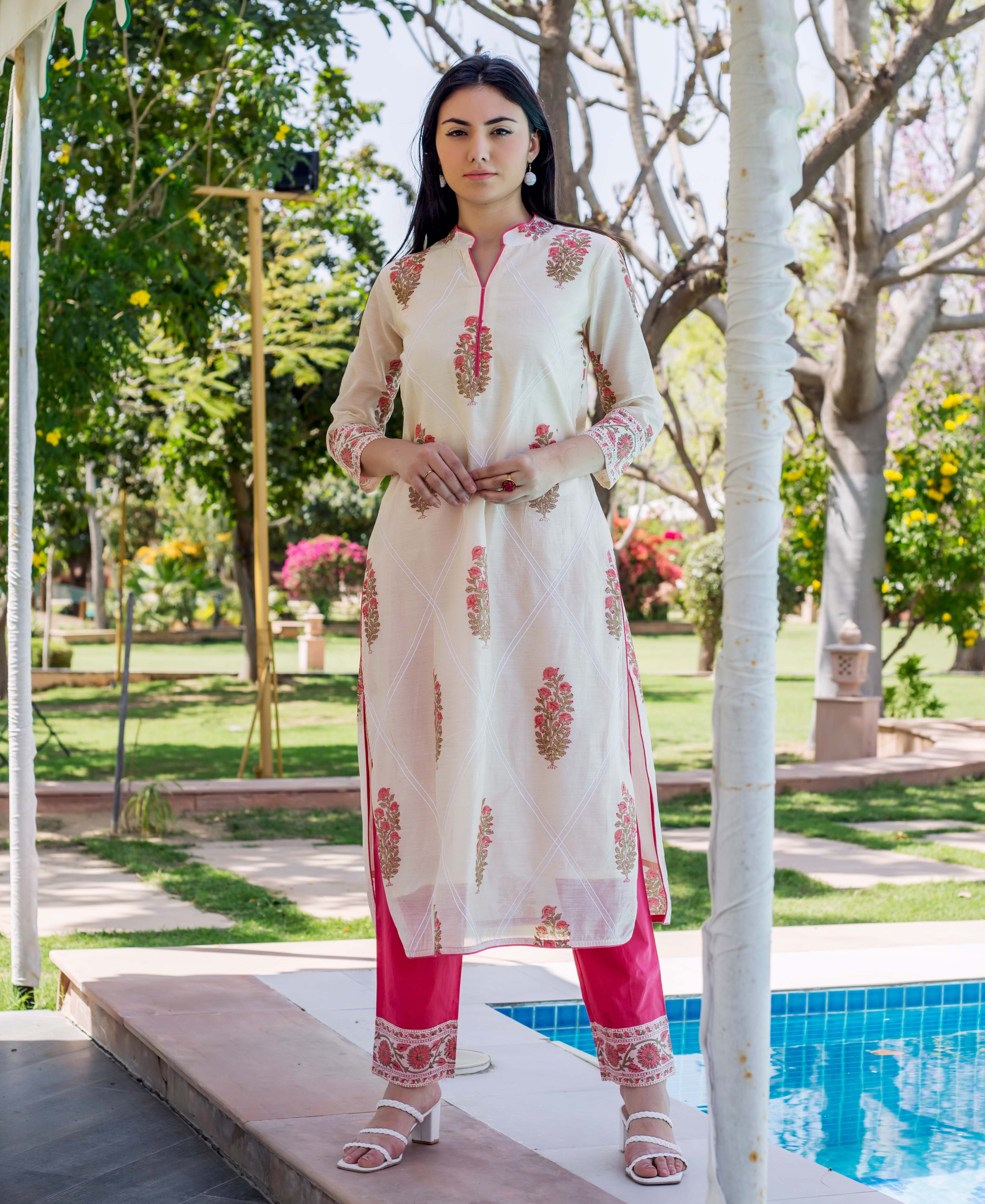 Standing model in off-white hand-block printed kurta with pink embroidery and bright pink pants.