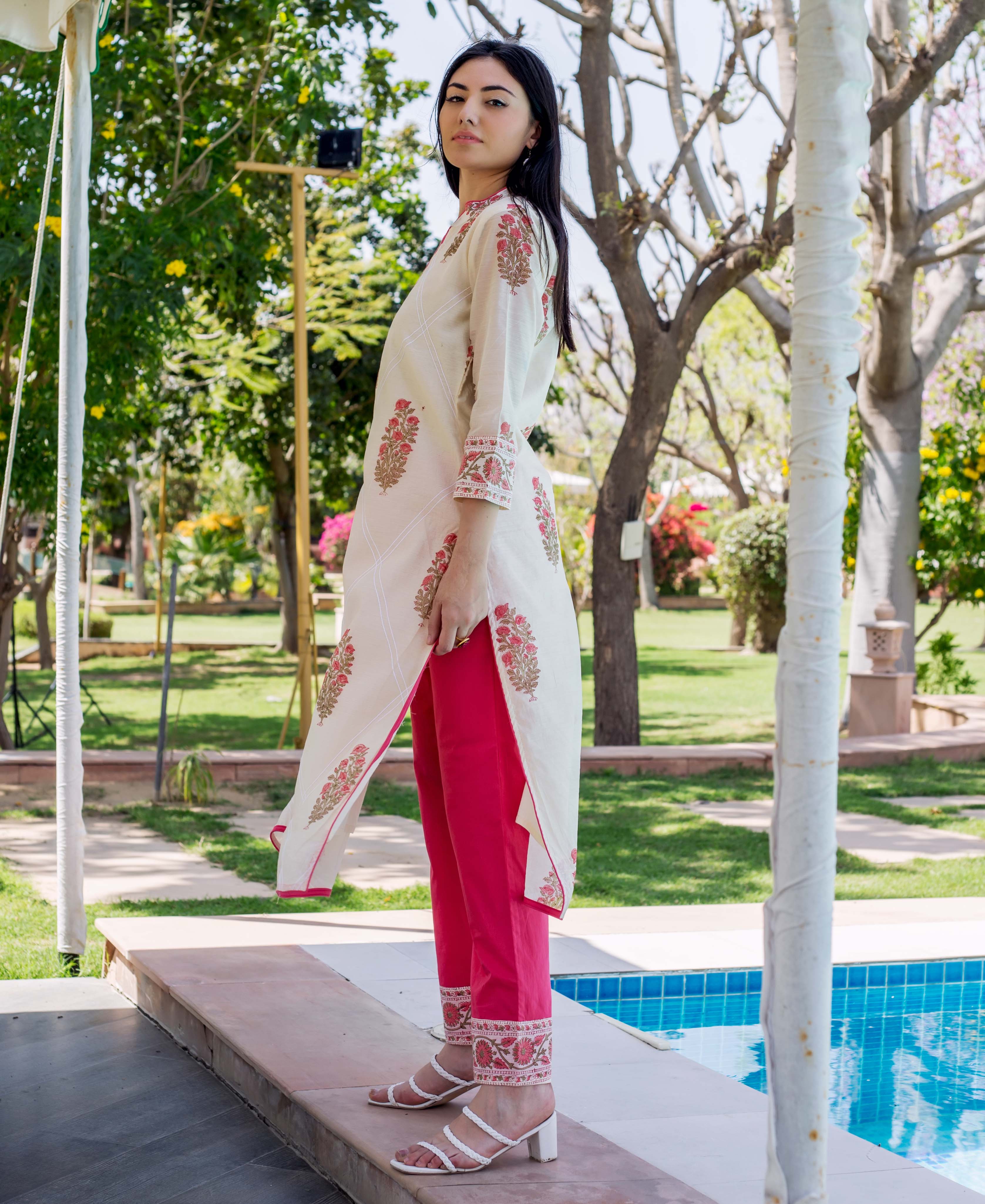 Woman in cream hand-block printed Mehr kurta and hot pink embroidered pants.