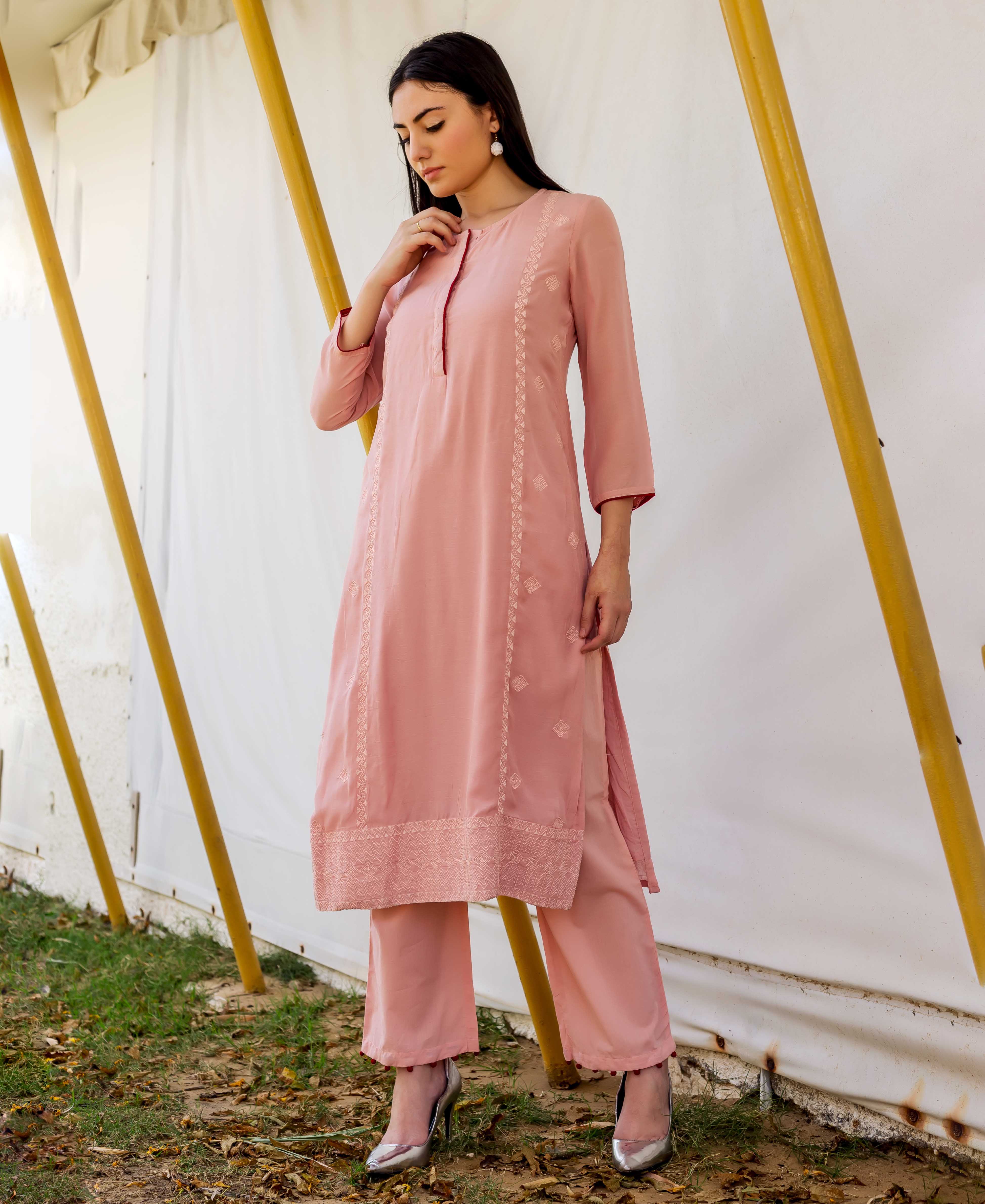 Woman wearing dusty pink embroidered straight kurta and matching pants, posing outdoors.