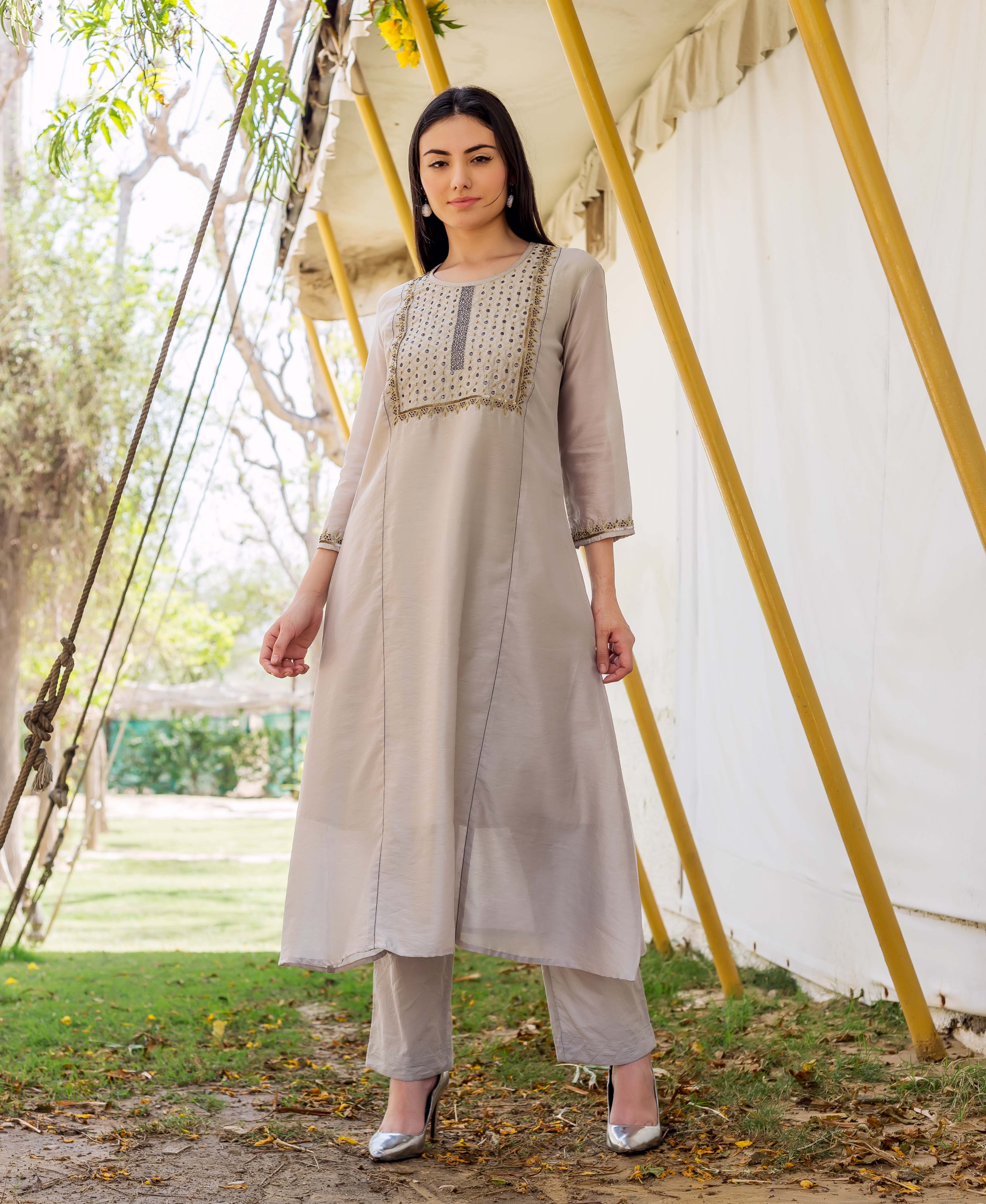 Front full look of a model wearing a light grey embroidered kurta and matching bottoms.