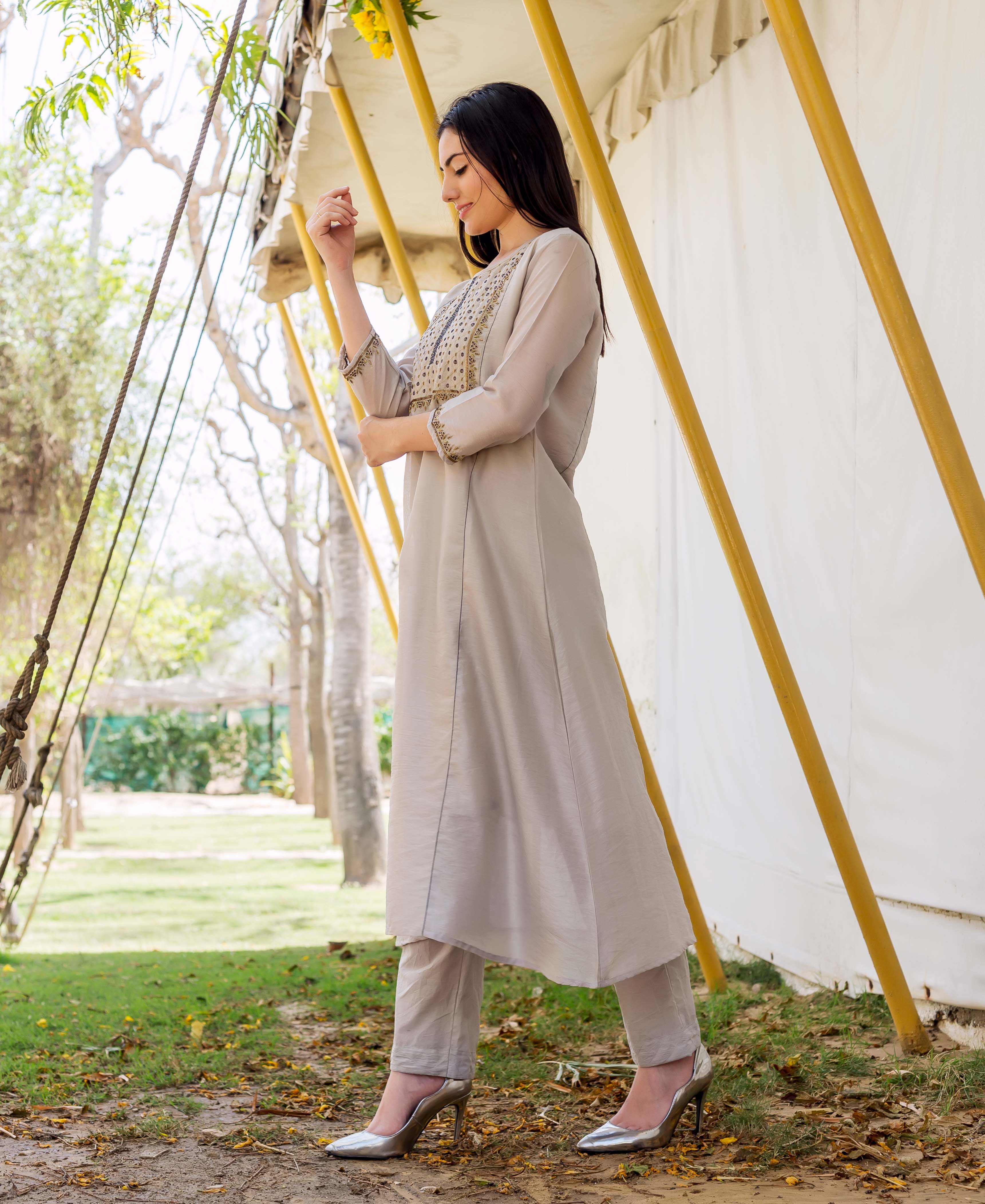 Side view of model wearing a light grey kurta and pants with embroidered yoke.