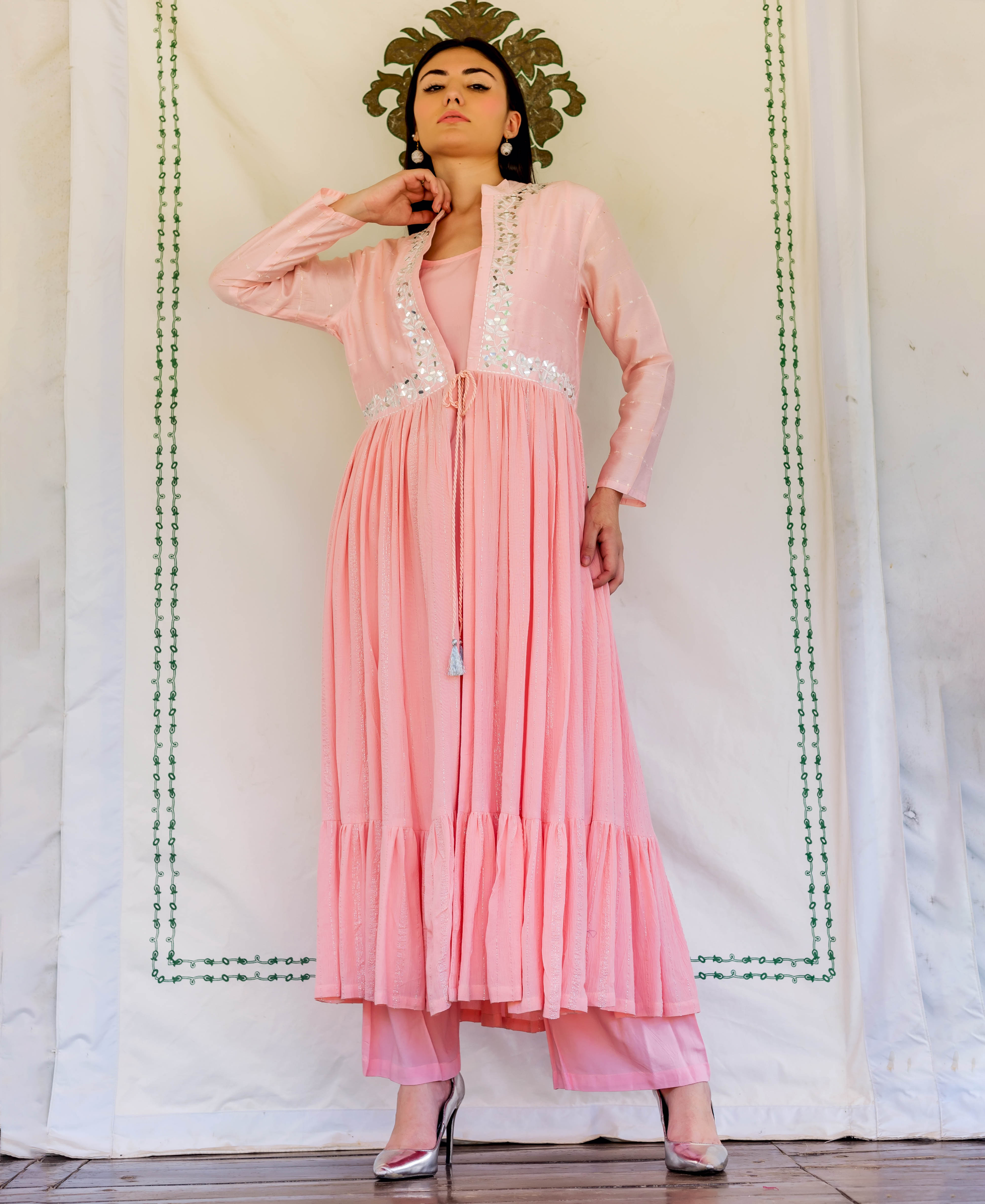 Full-length model wears flamingo pink hand-block printed tiered kurta with mirror-work jacket.