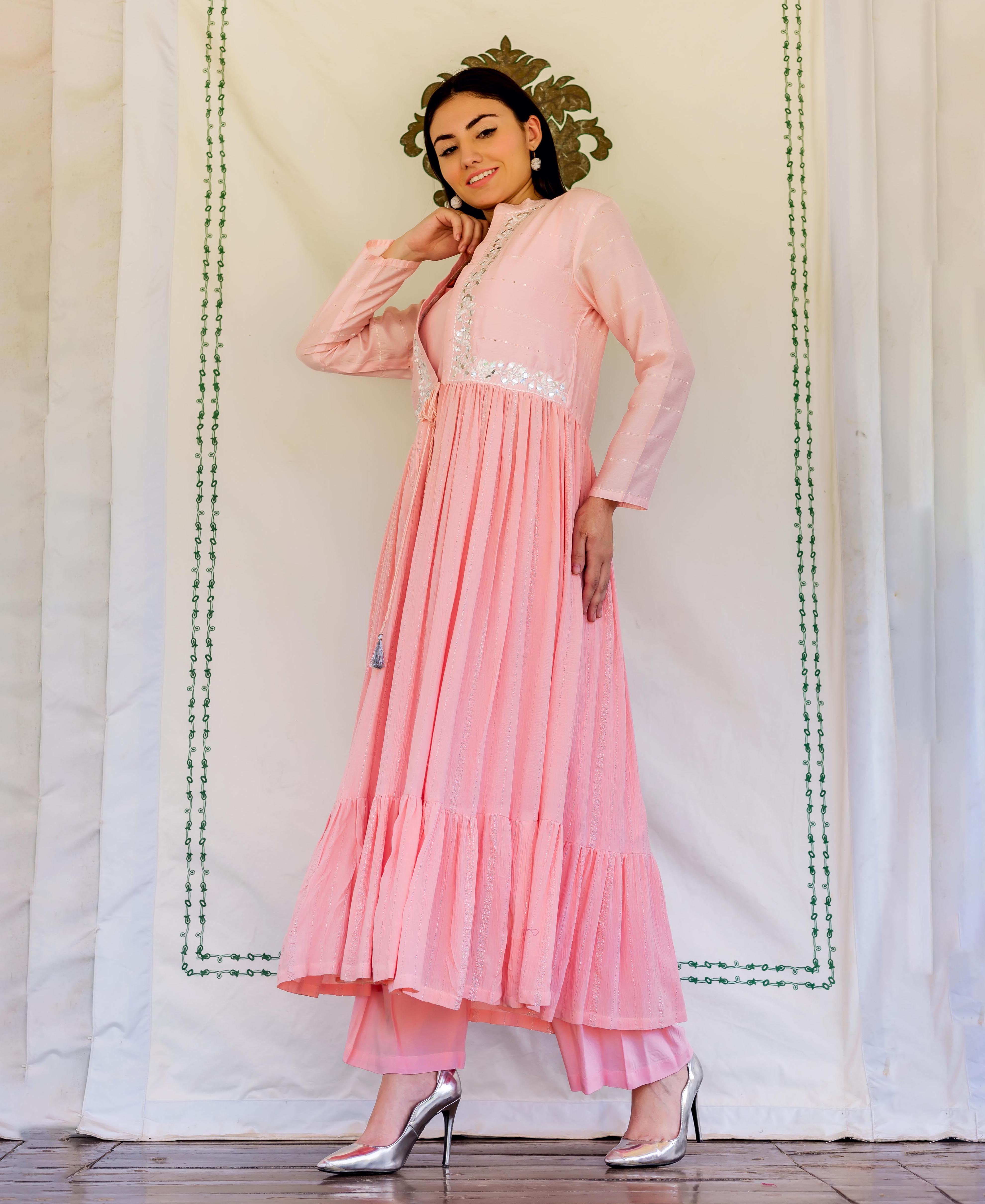 Full-length model in flamingo pink embroidered kurta, with mirror work and ruffled hem.