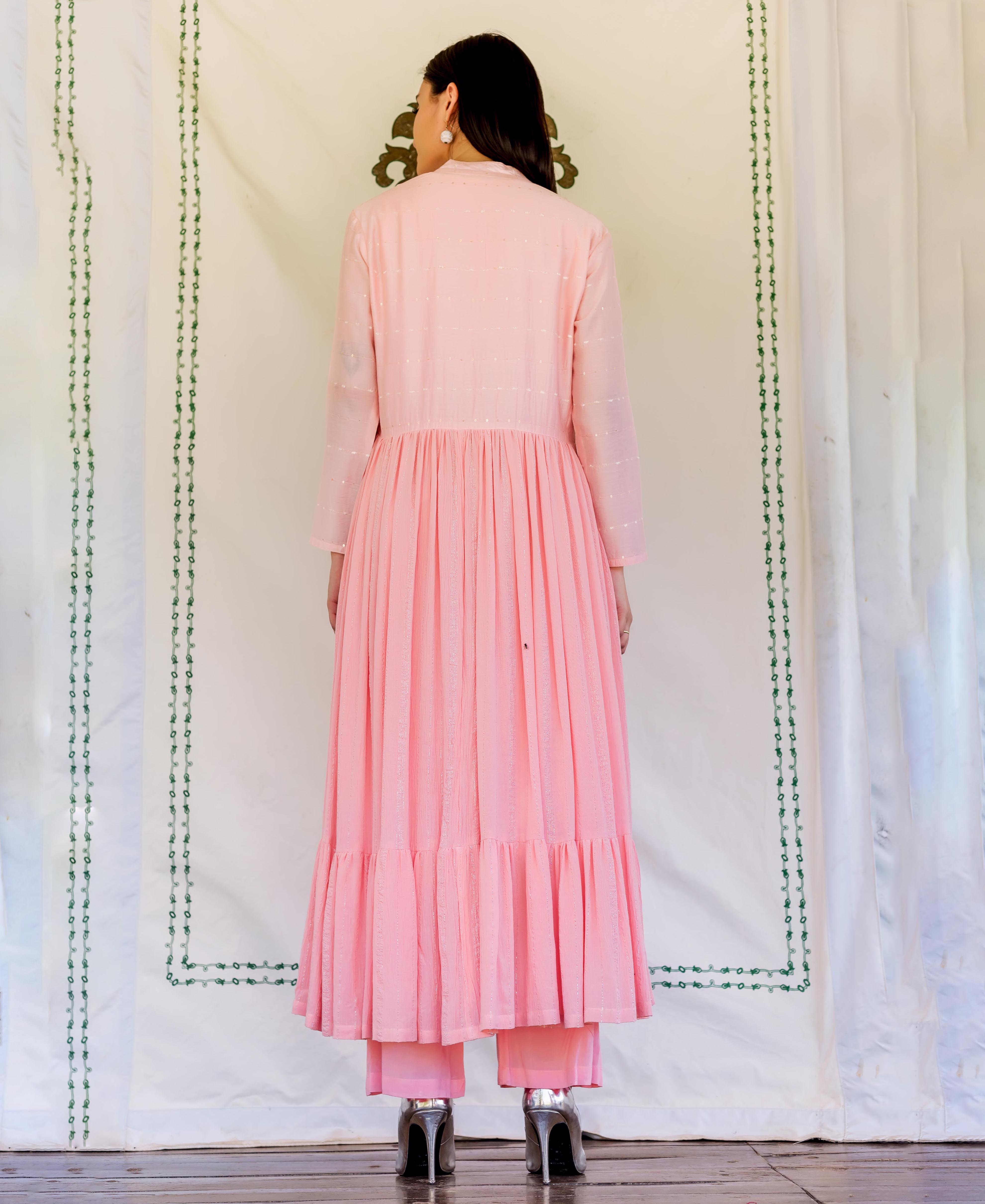 A model wearing a long, pink, embroidered kurta with a ruffled hem.