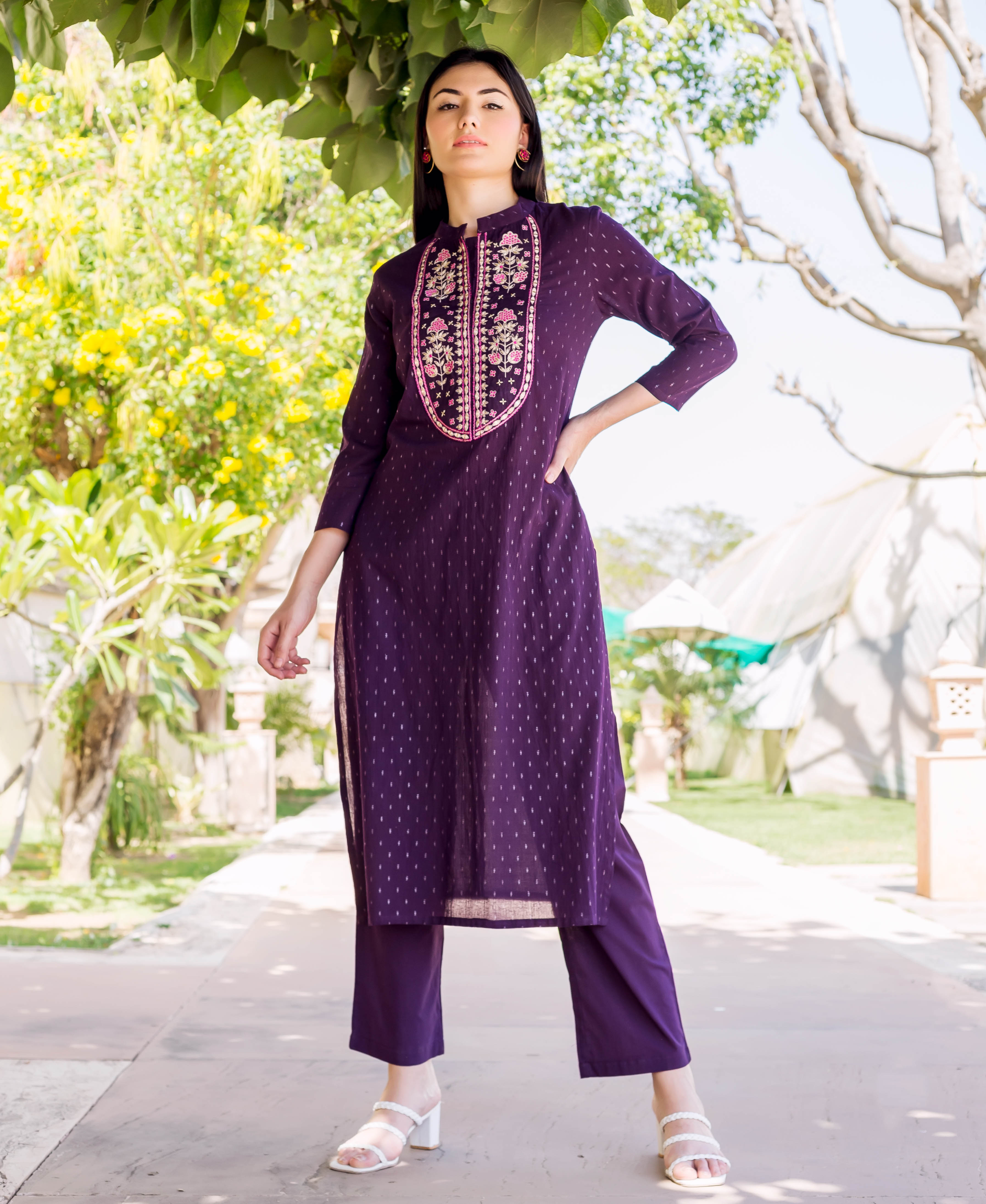 Woman wears wine lurex dotted straight kurta with detailed embroidered neckline and matching pants.