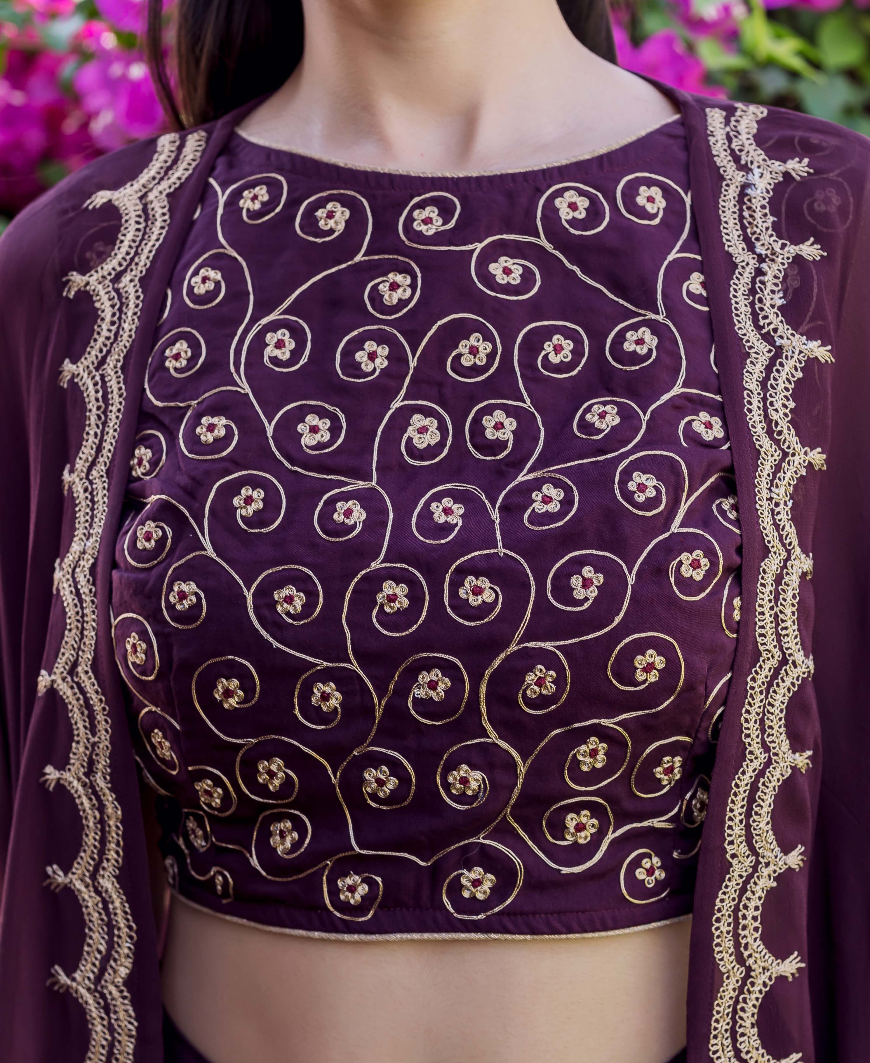 Front close-up of a model in a wine crop top and jacket with golden Dori embroidery.